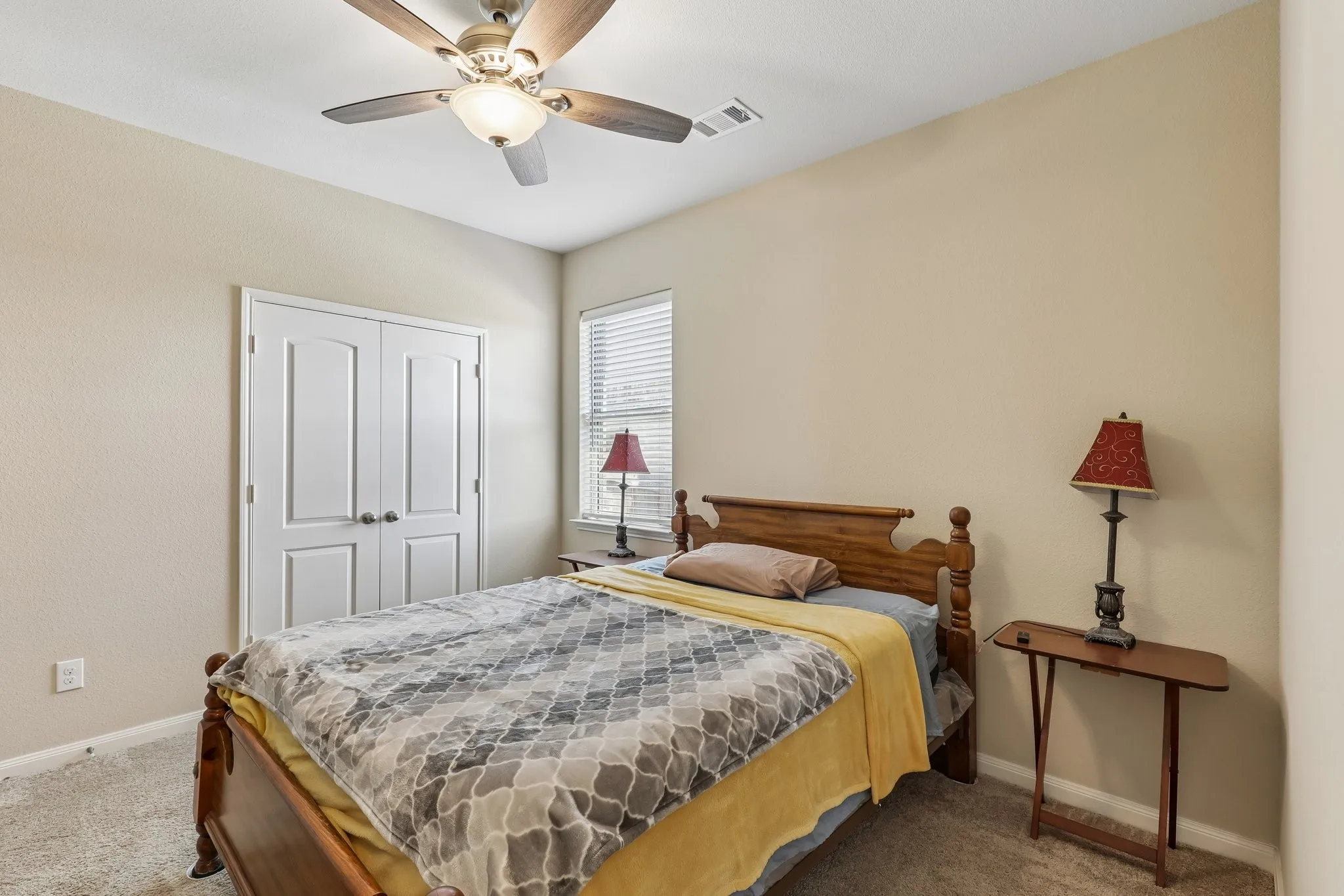 Ceiling fan with integrated lighting, window with blinds, bi-fold closet doors, and neutral-toned wall paint