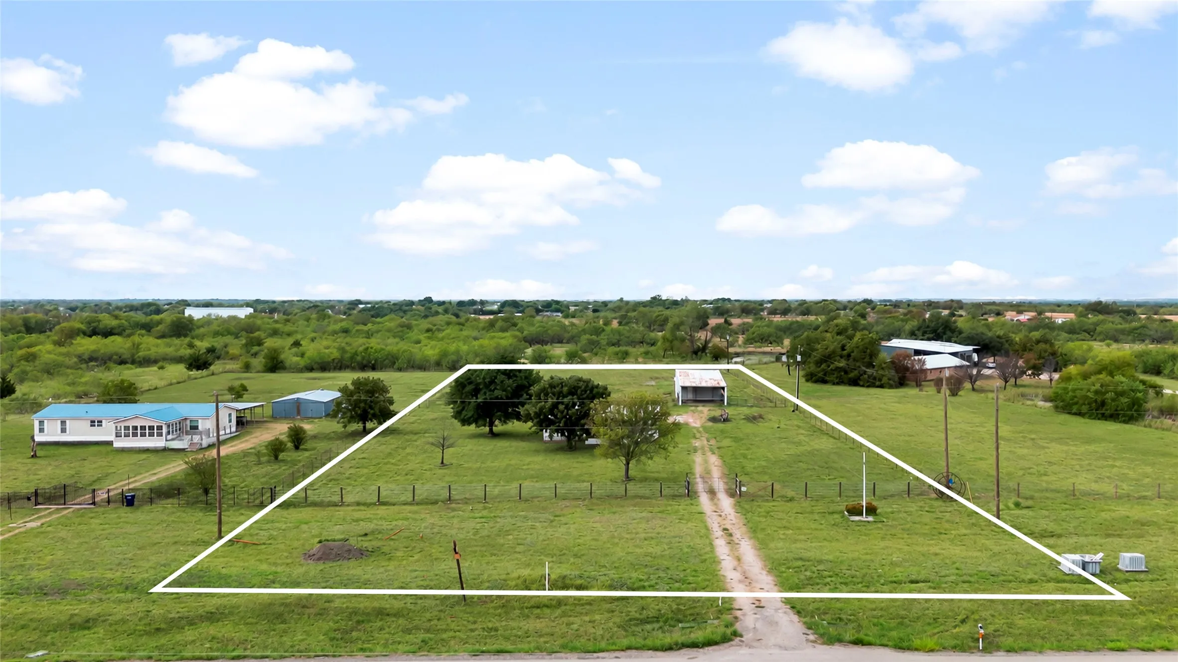 Expansive green space featuring mature trees and a gravel driveway