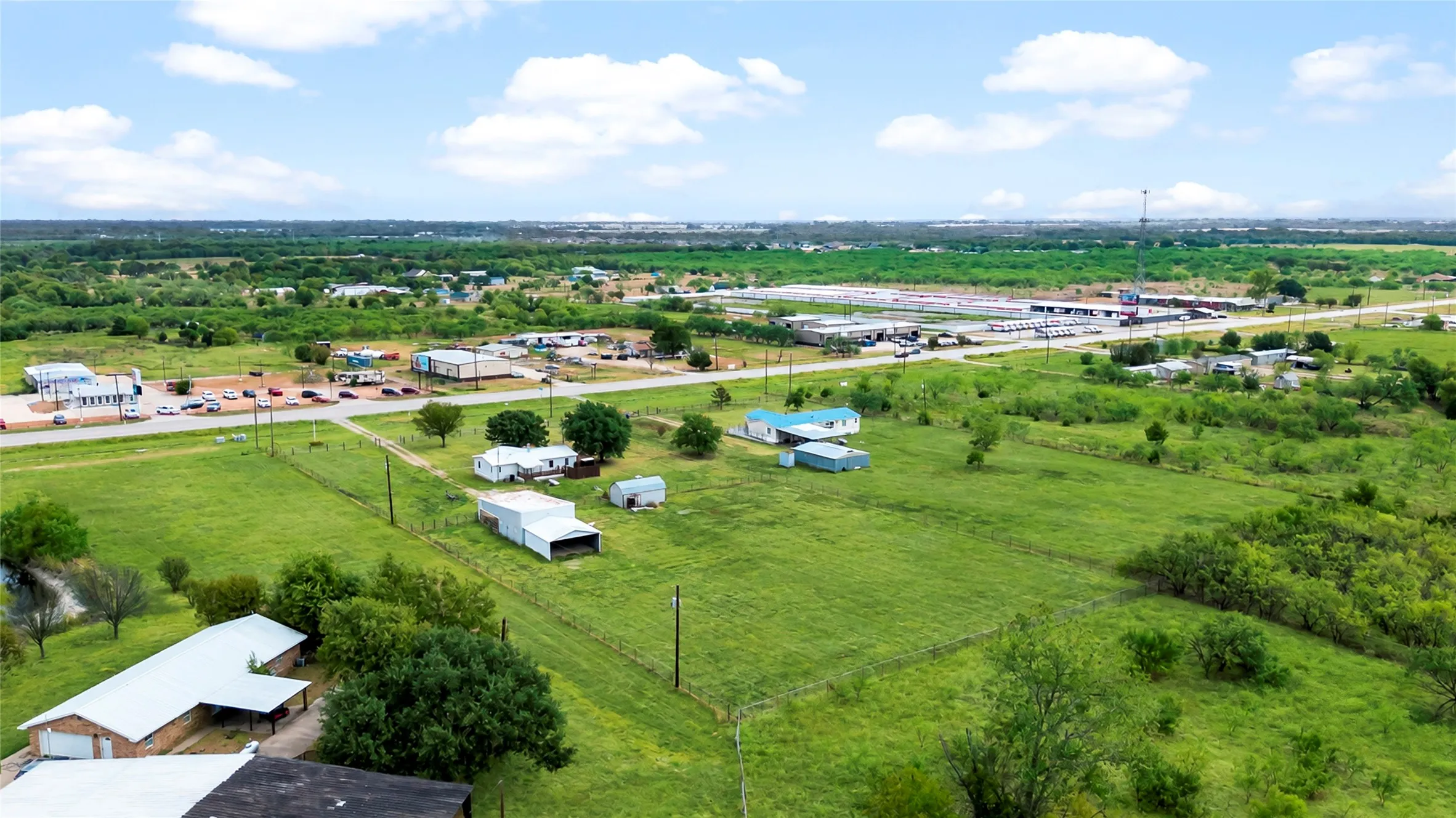 Expansive green acreage with scattered trees, bordered by a roadway