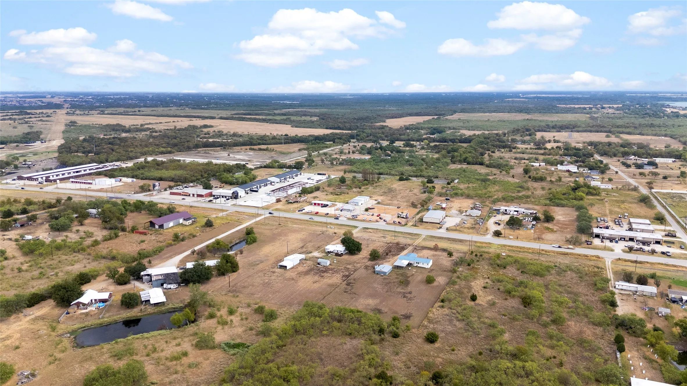 Expansive acreage with a pond, surrounding undeveloped land, and established roadways