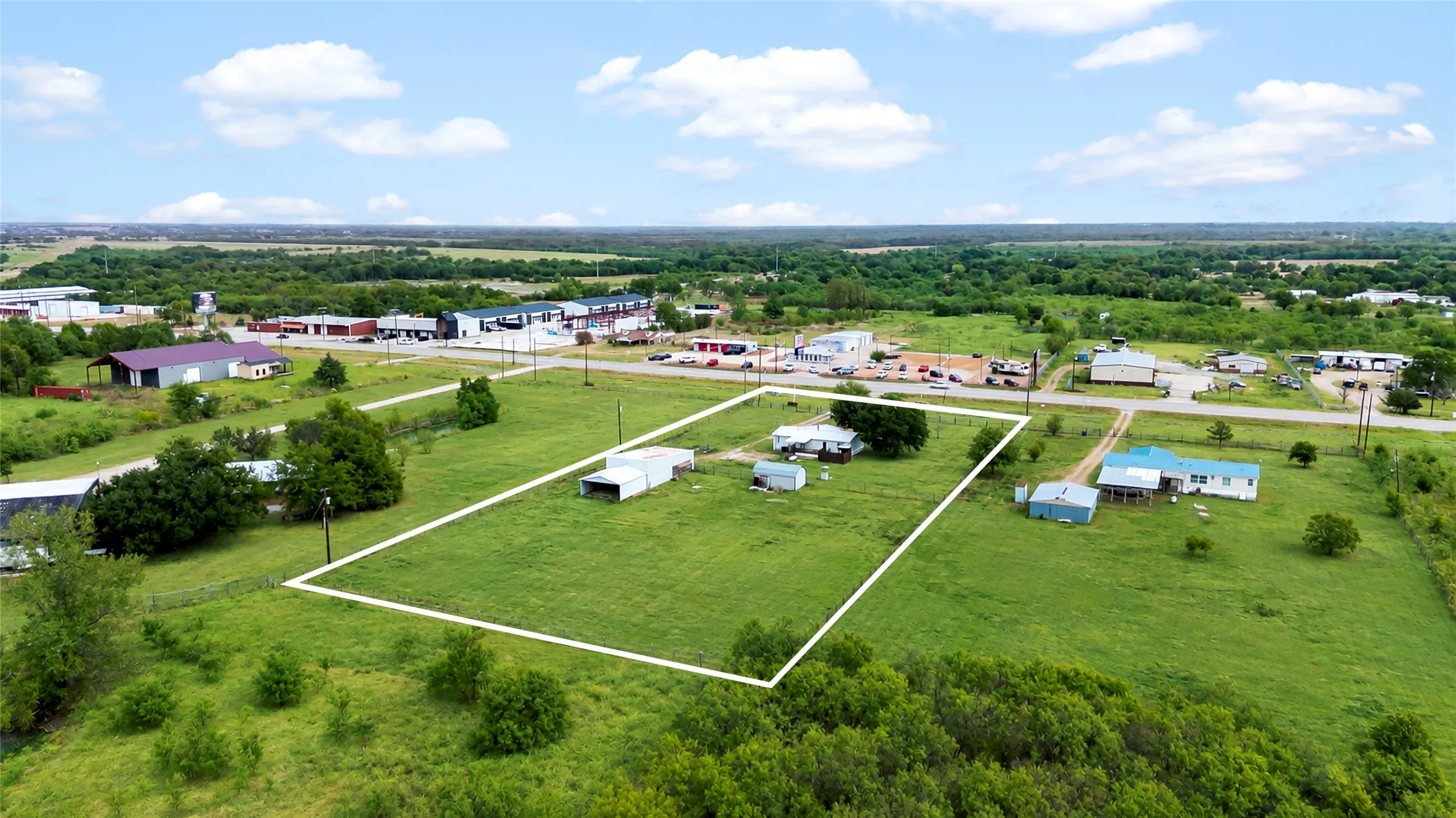 Expansive green landscape with a single-story residence and multiple outbuildings