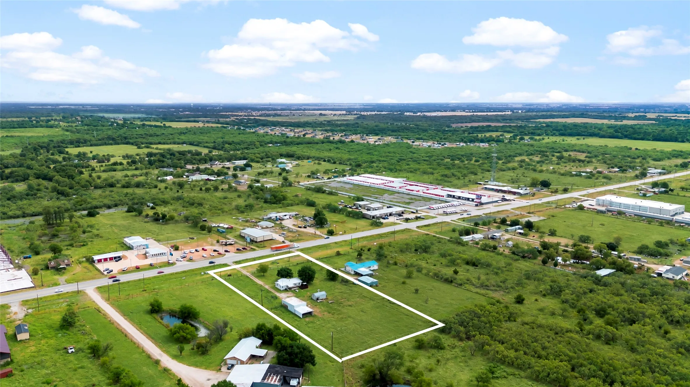 Expansive lot featuring multiple structures, open green space, and direct road frontage