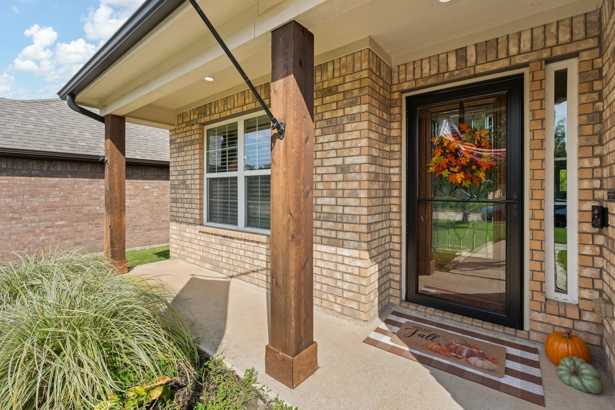 Wood-finish flooring, accent wall with geometric paneling, ceiling fan with integrated lighting, dual pane window with blinds, and paneled bifold doors