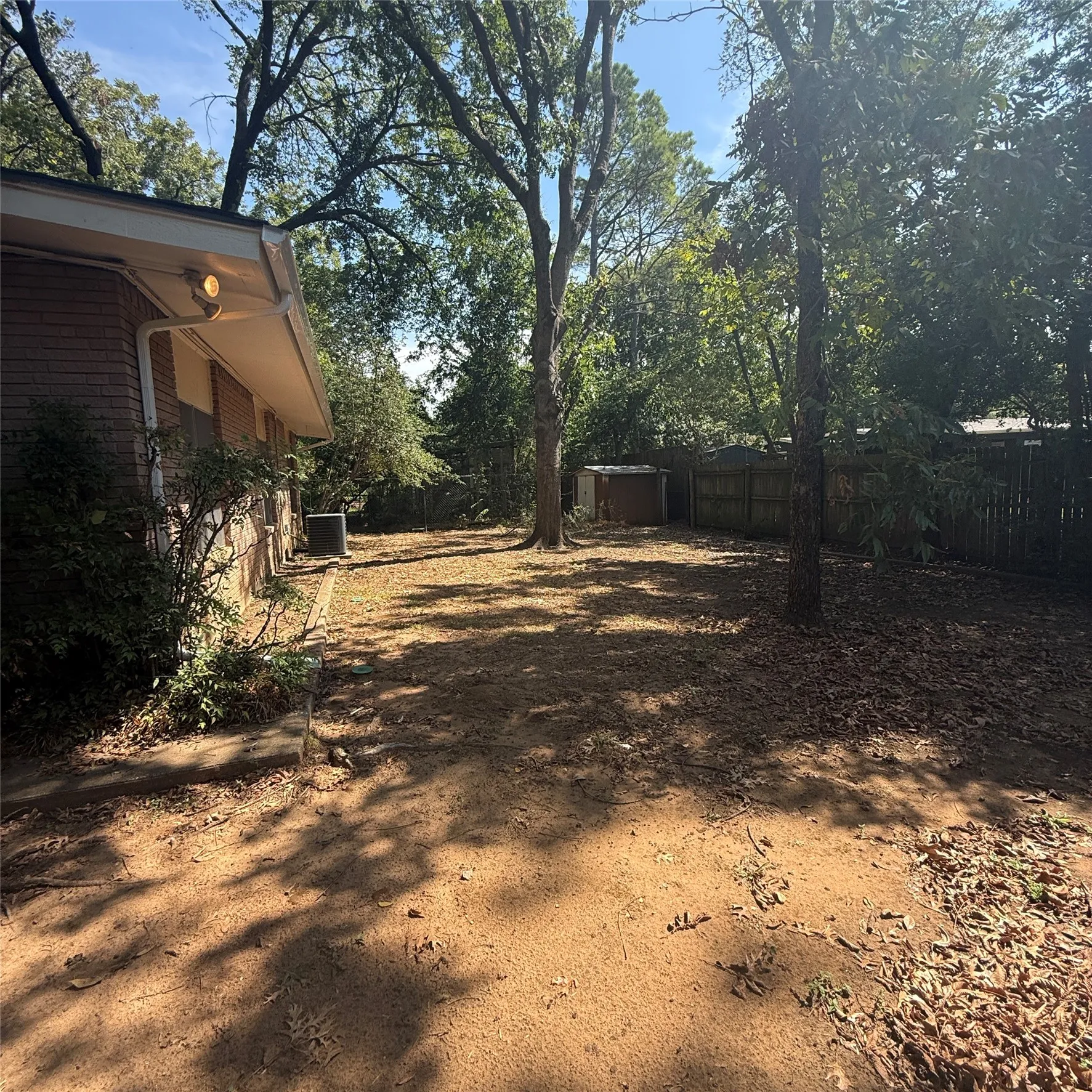 Expansive backyard with mature trees, a privacy fence, and a storage shed