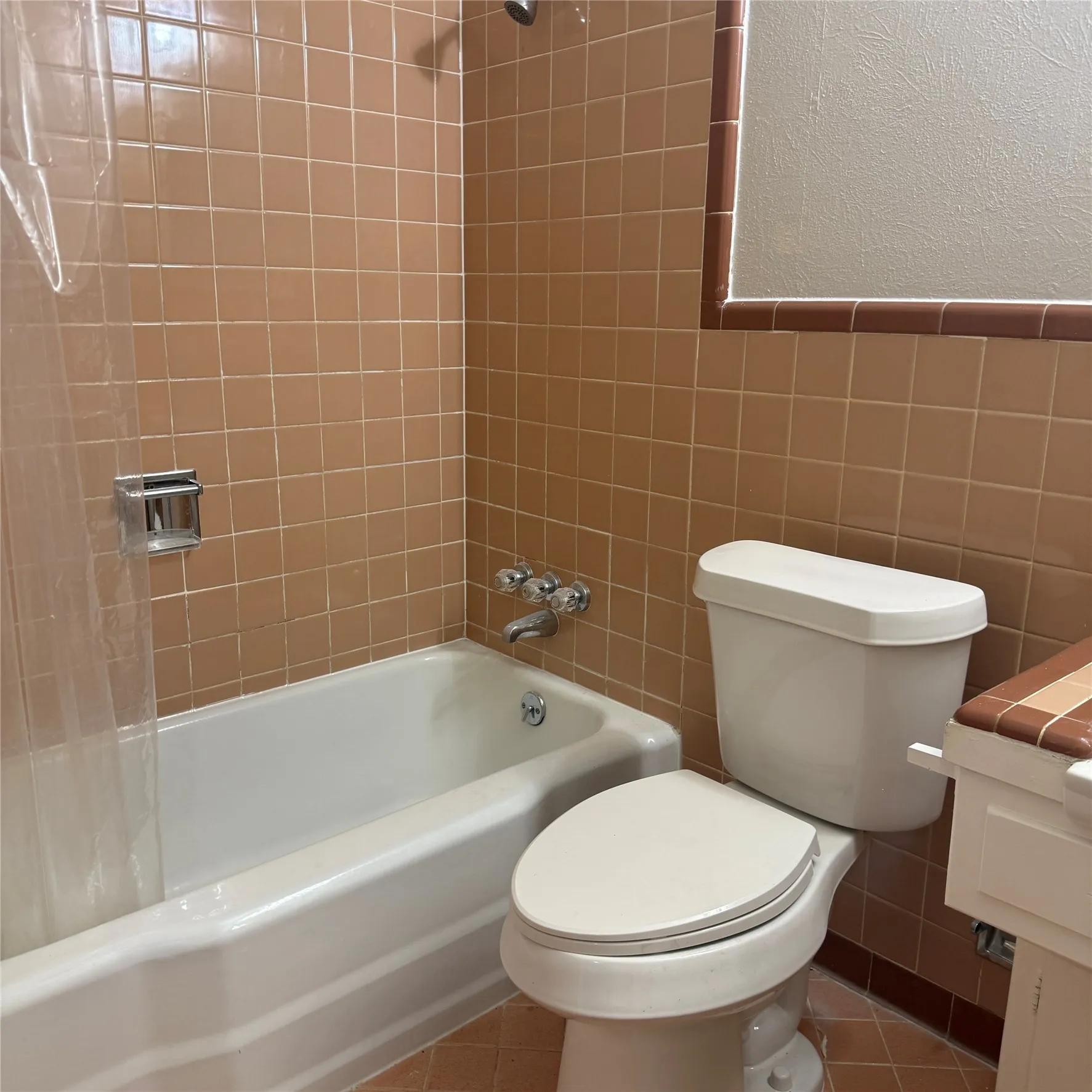 Bathroom featuring a white bathtub, toilet, and vanity with a tiled countertop