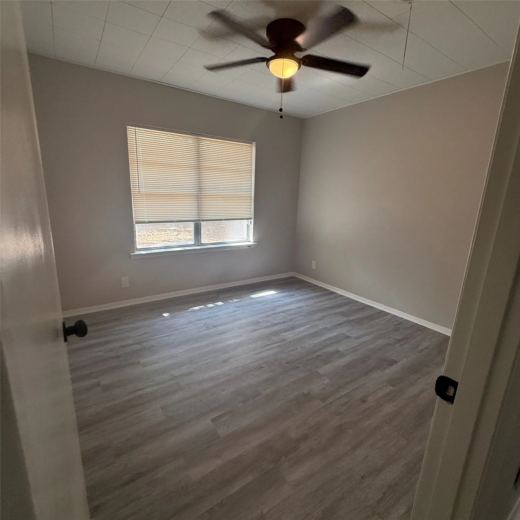 Recessed window with blinds, wood-finish flooring, and ceiling fan with light fixture