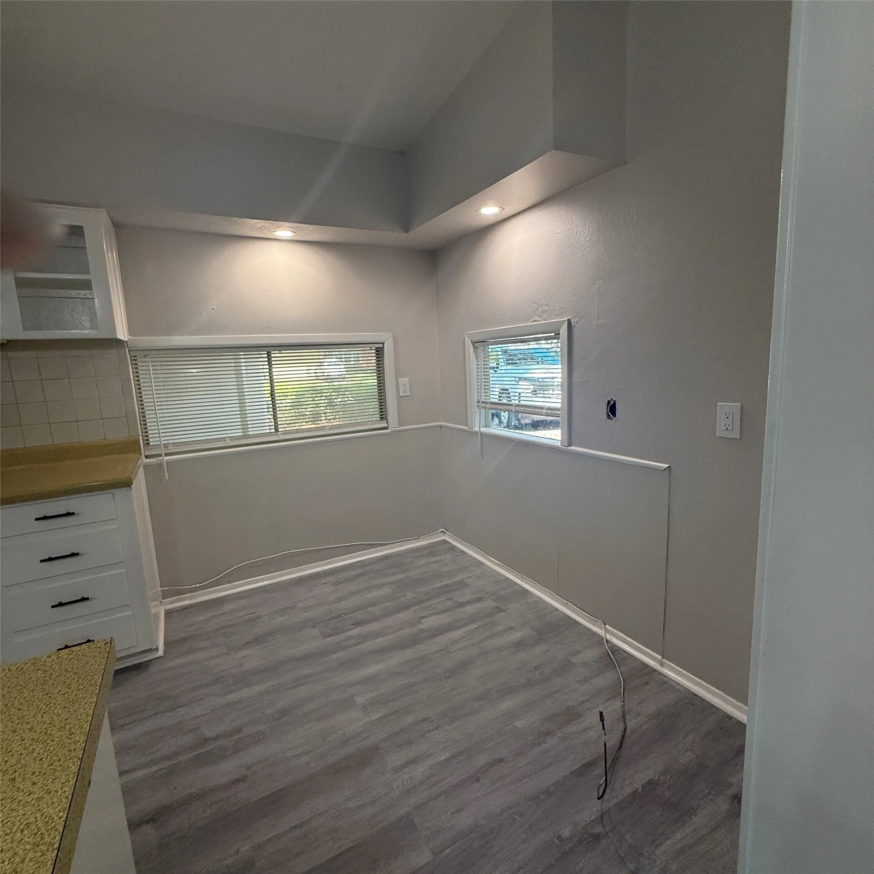 Wood-finish flooring, white cabinetry with dark hardware, and light-colored countertops