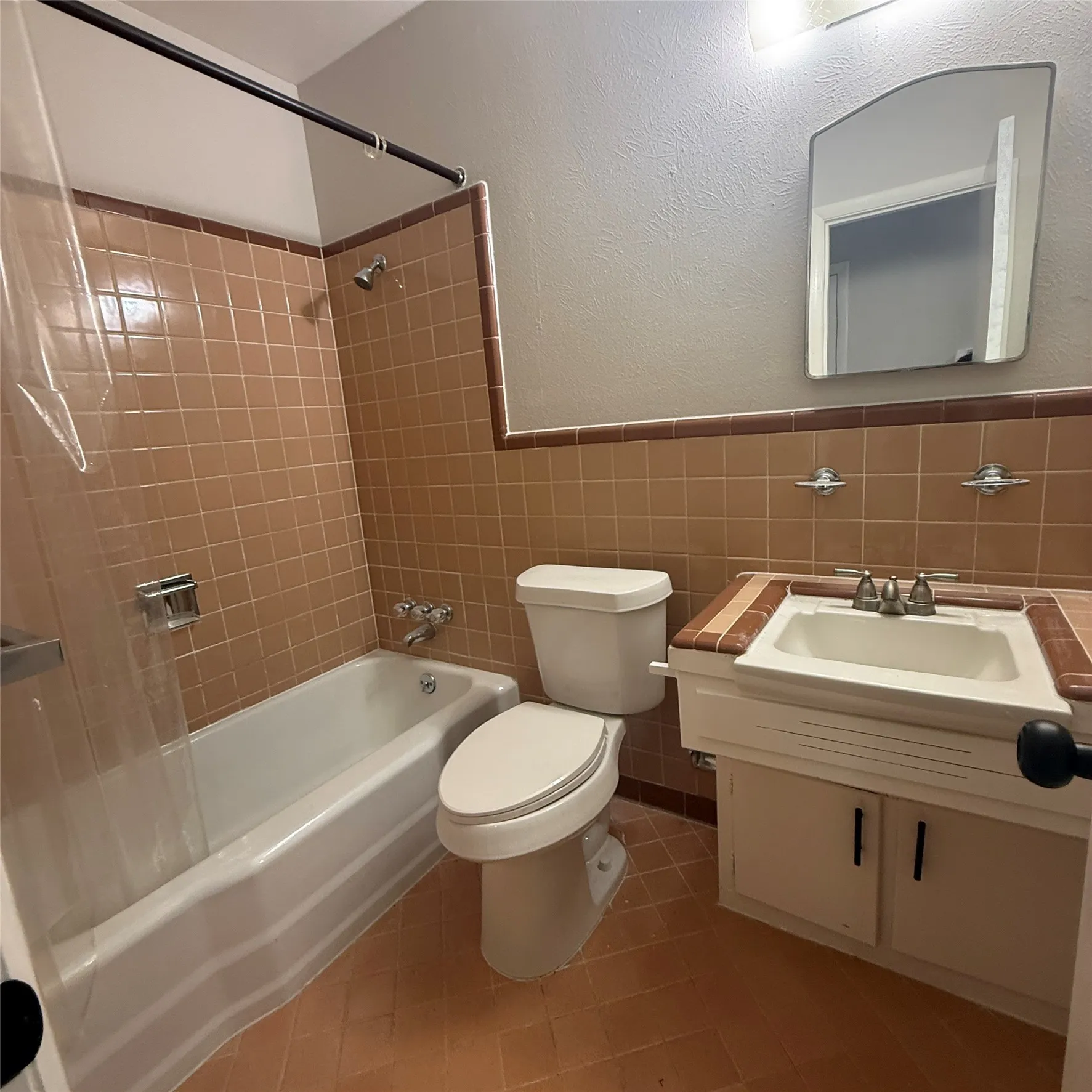 Bathroom with tile flooring, tiled shower surround, integrated bathtub, and a vanity with an integrated sink