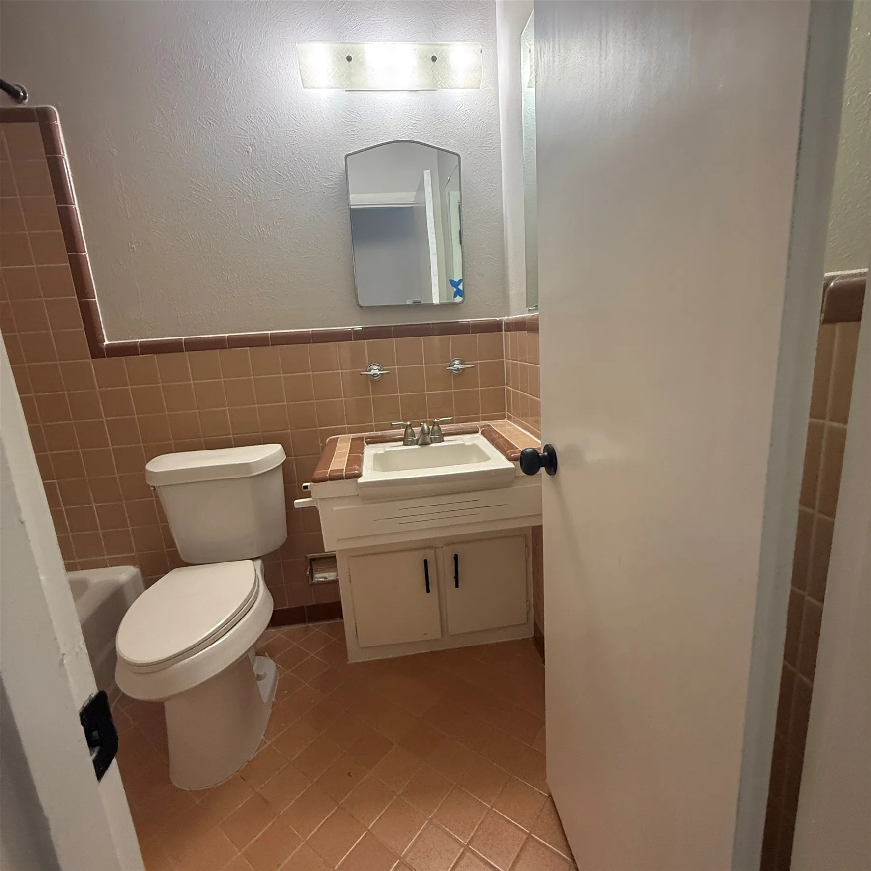 Bathroom featuring a tile floor, tile wainscoting, and a single vanity with an integrated sink