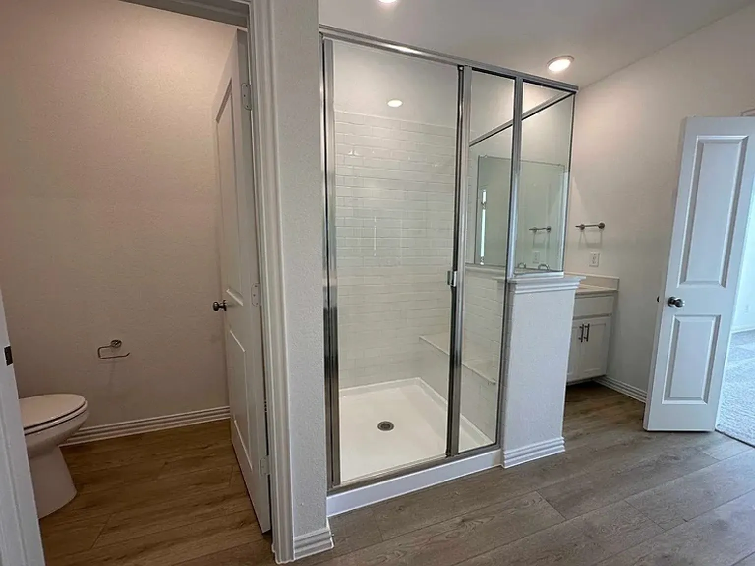 Glass-enclosed shower with subway tile surround and integrated bench