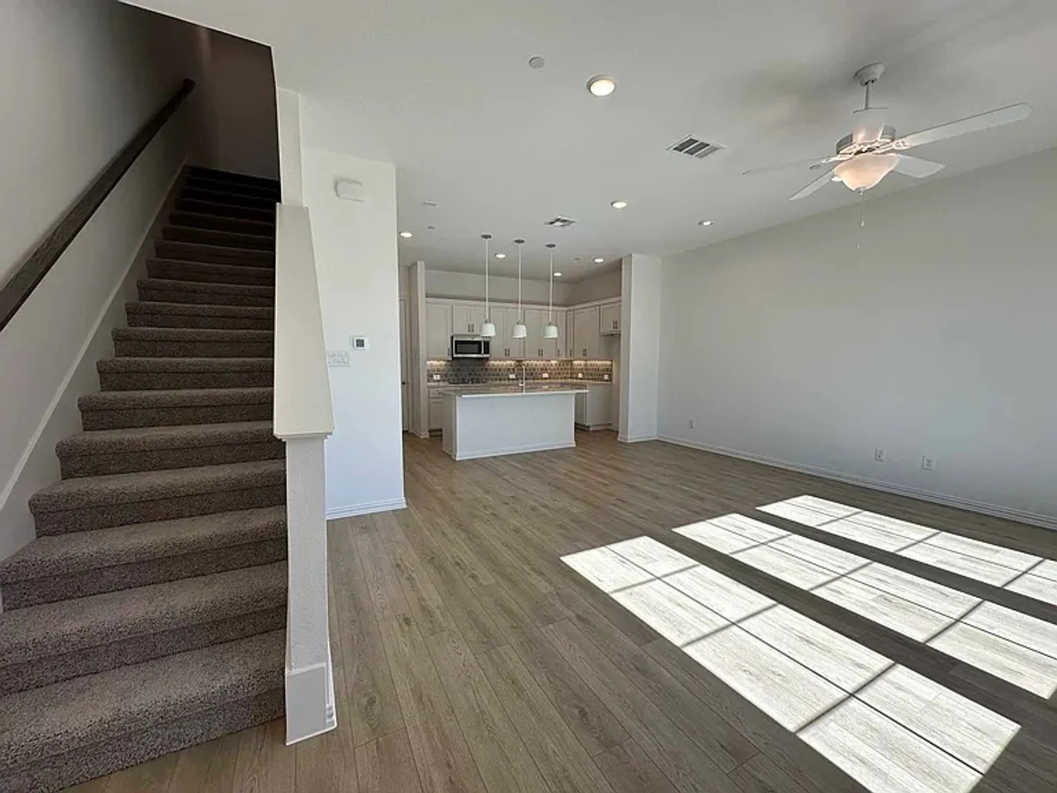 Open-concept living space with wood-finish flooring and a ceiling fan