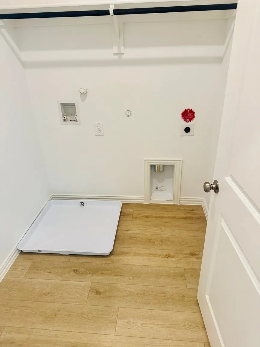 Dedicated laundry area featuring wood-finish flooring, white walls, and a utility basin