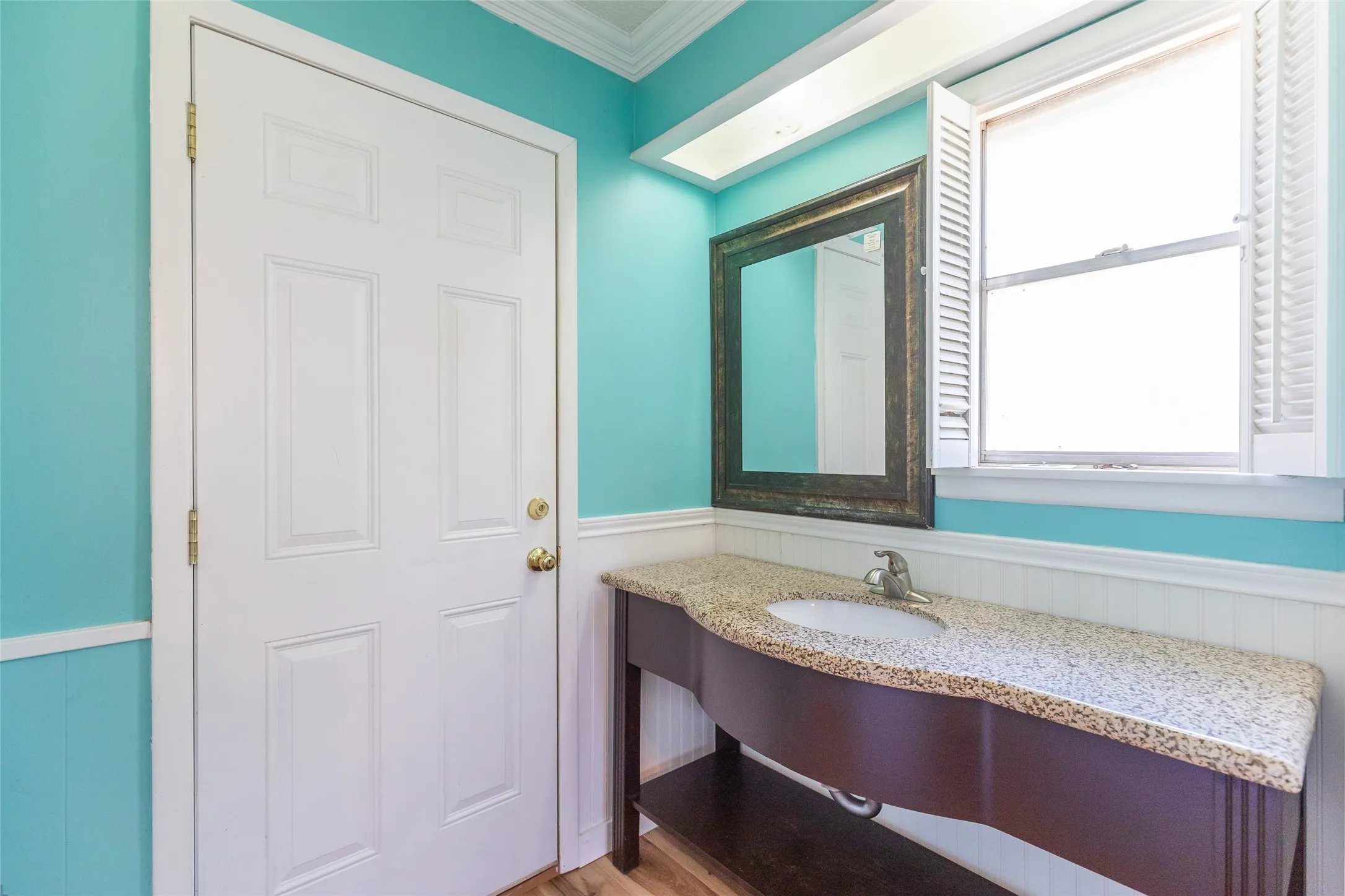 Custom vanity with granite countertop and integrated sink, framed mirror, and wood-finish flooring