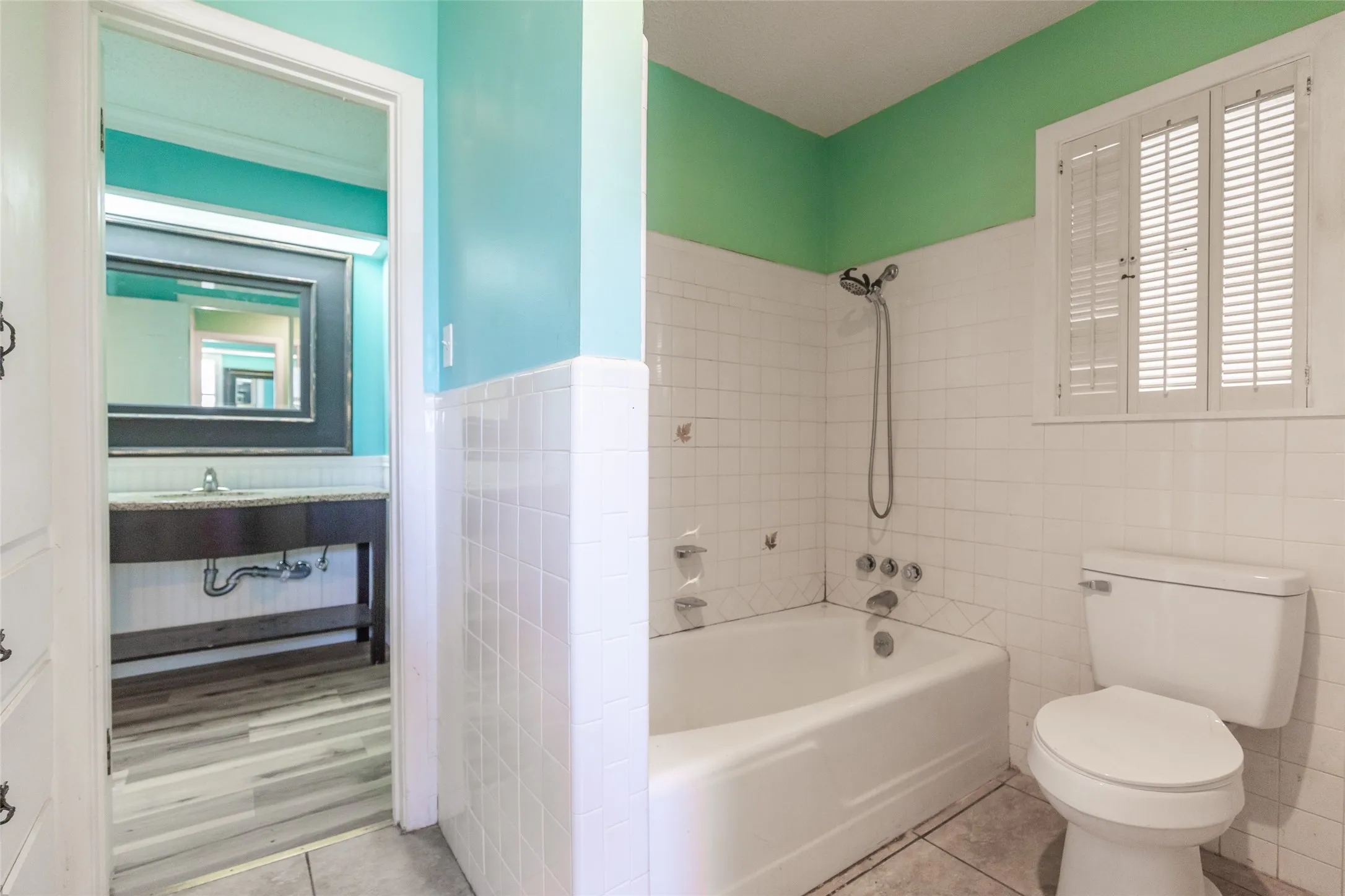 Bathroom featuring a built-in bathtub, white subway tile surround, and a vanity with a surface-mounted sink