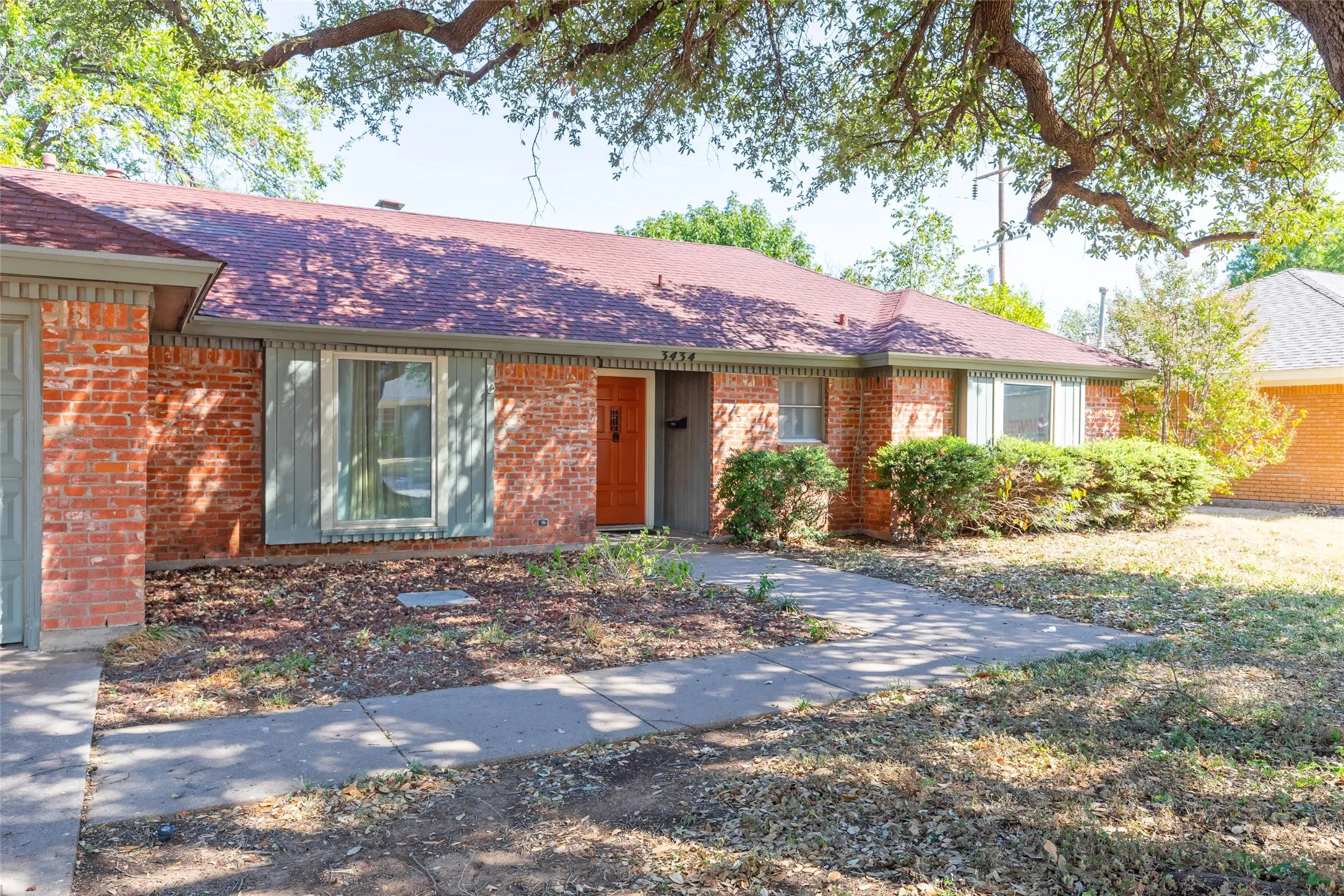 Brick exterior with a red shingle roof, complemented by a concrete walkway