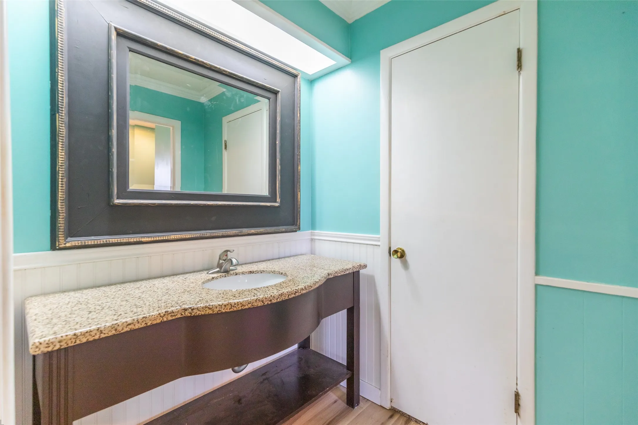 Vanity with a speckled countertop, integrated sink, and dark wood-finish base