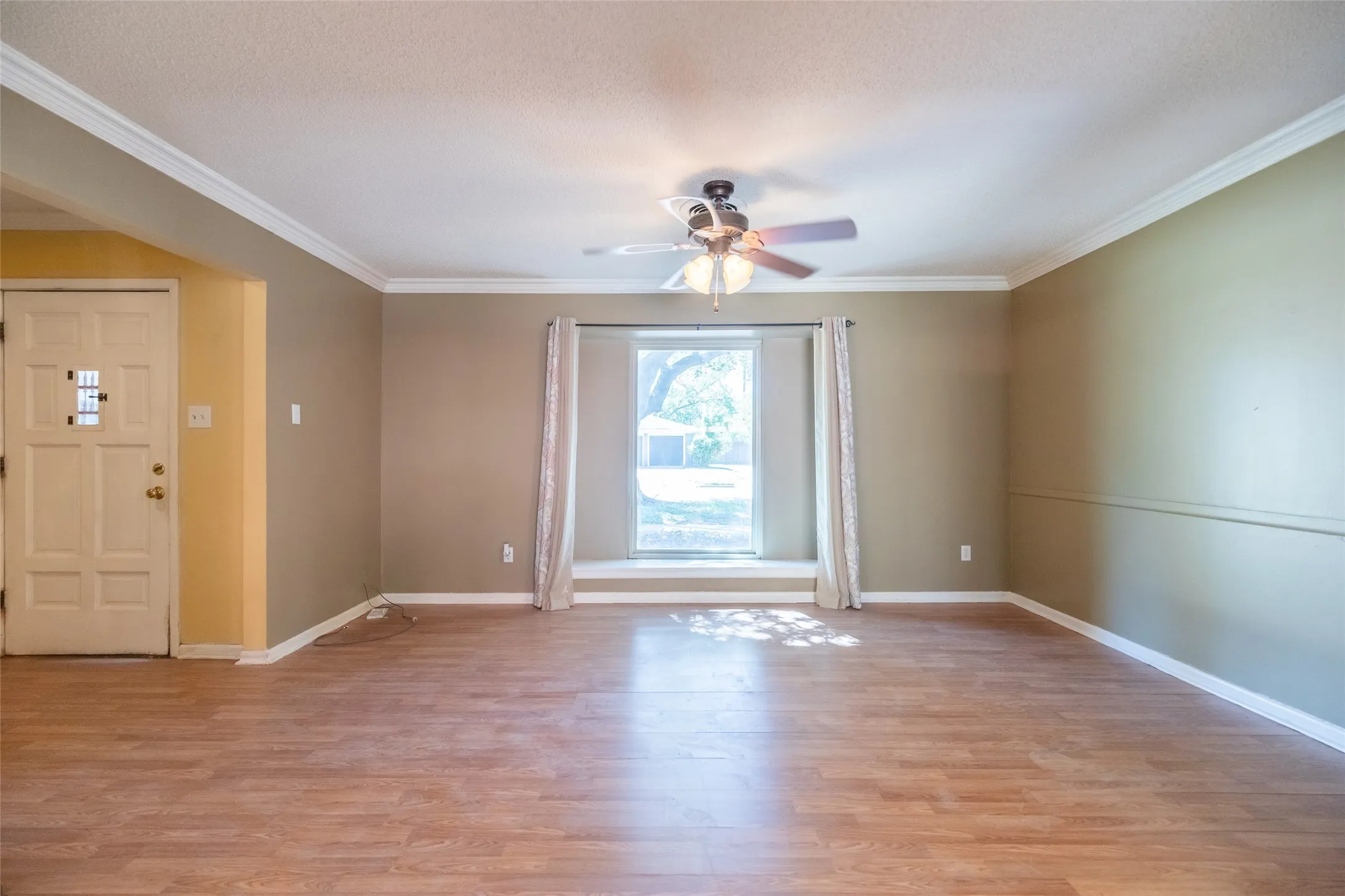 Wood-finish flooring throughout, crown molding, and a ceiling fan with light fixture