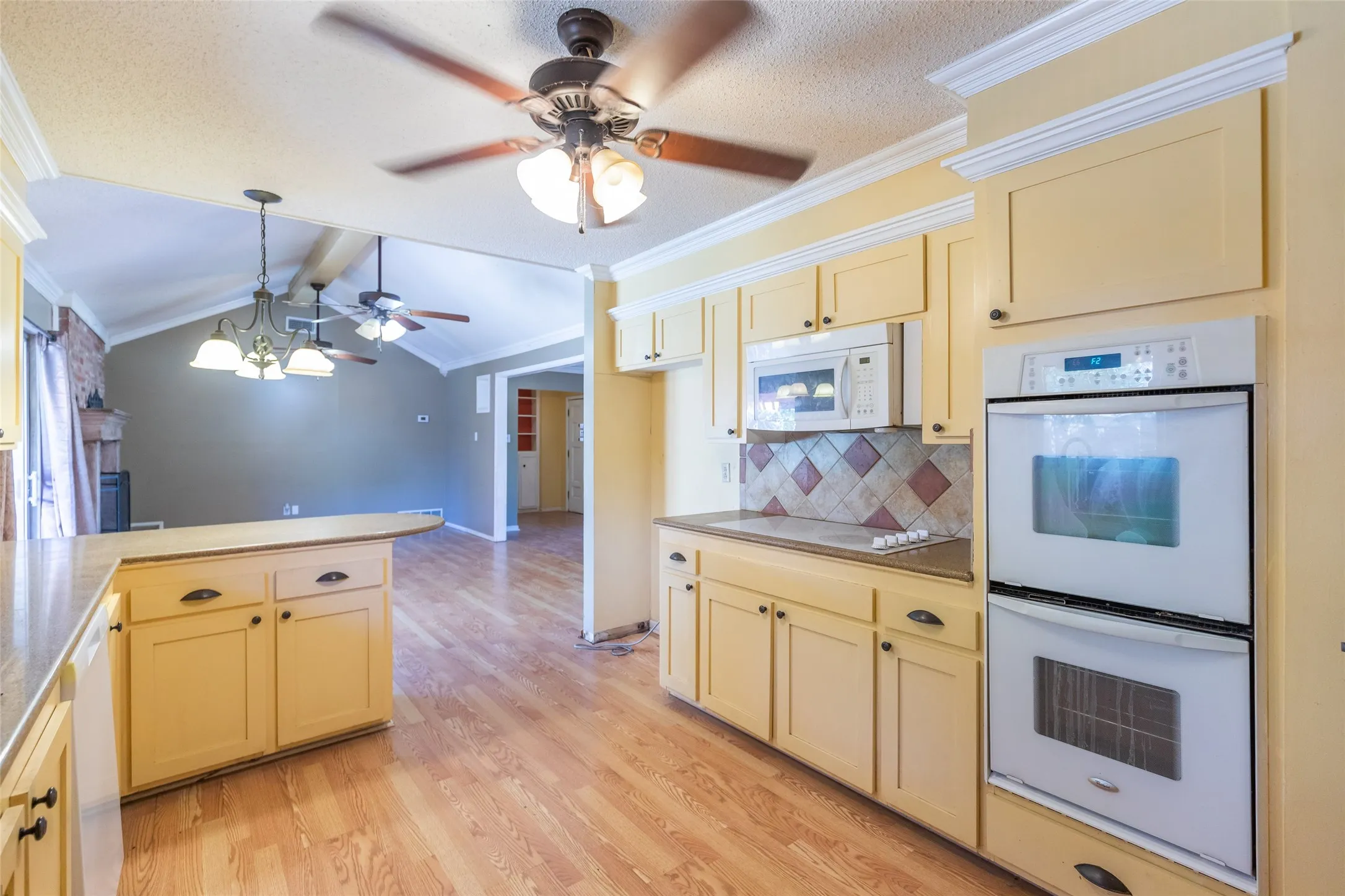 Kitchen featuring wood-finish flooring, built-in double oven, microwave, and custom cabinetry with dark hardware
