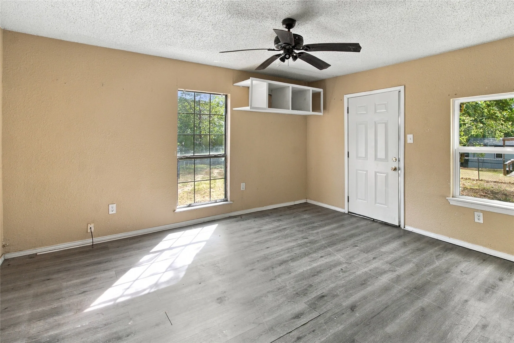 Wood-finish flooring, multiple windows providing natural light, built-in shelving, and a ceiling fan
