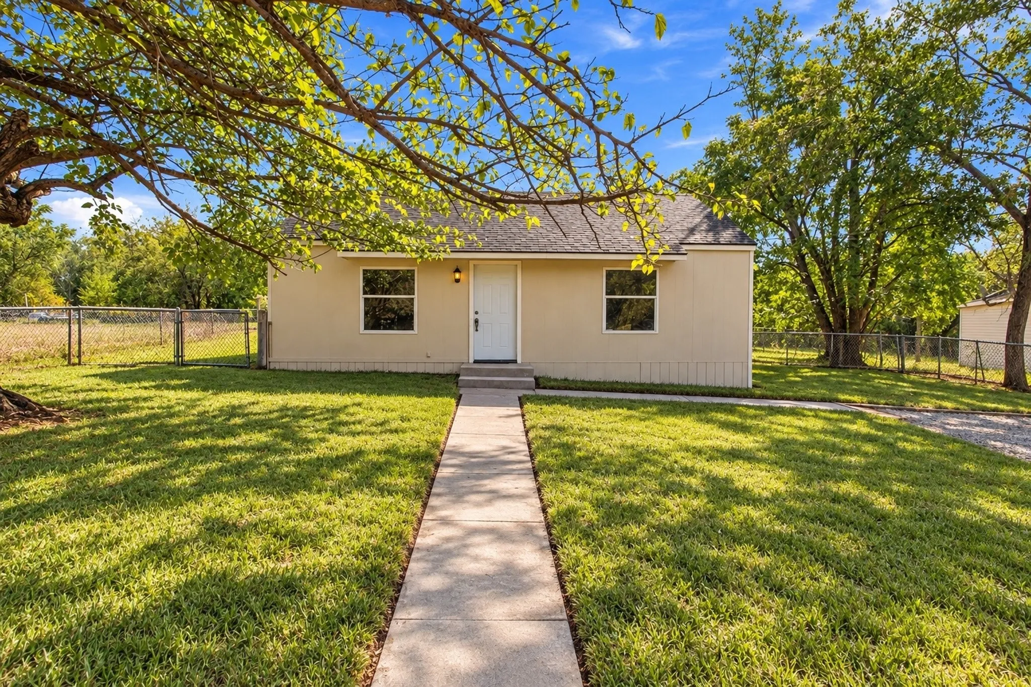 Single-story property with stucco exterior, a concrete walkway, and a gravel driveway