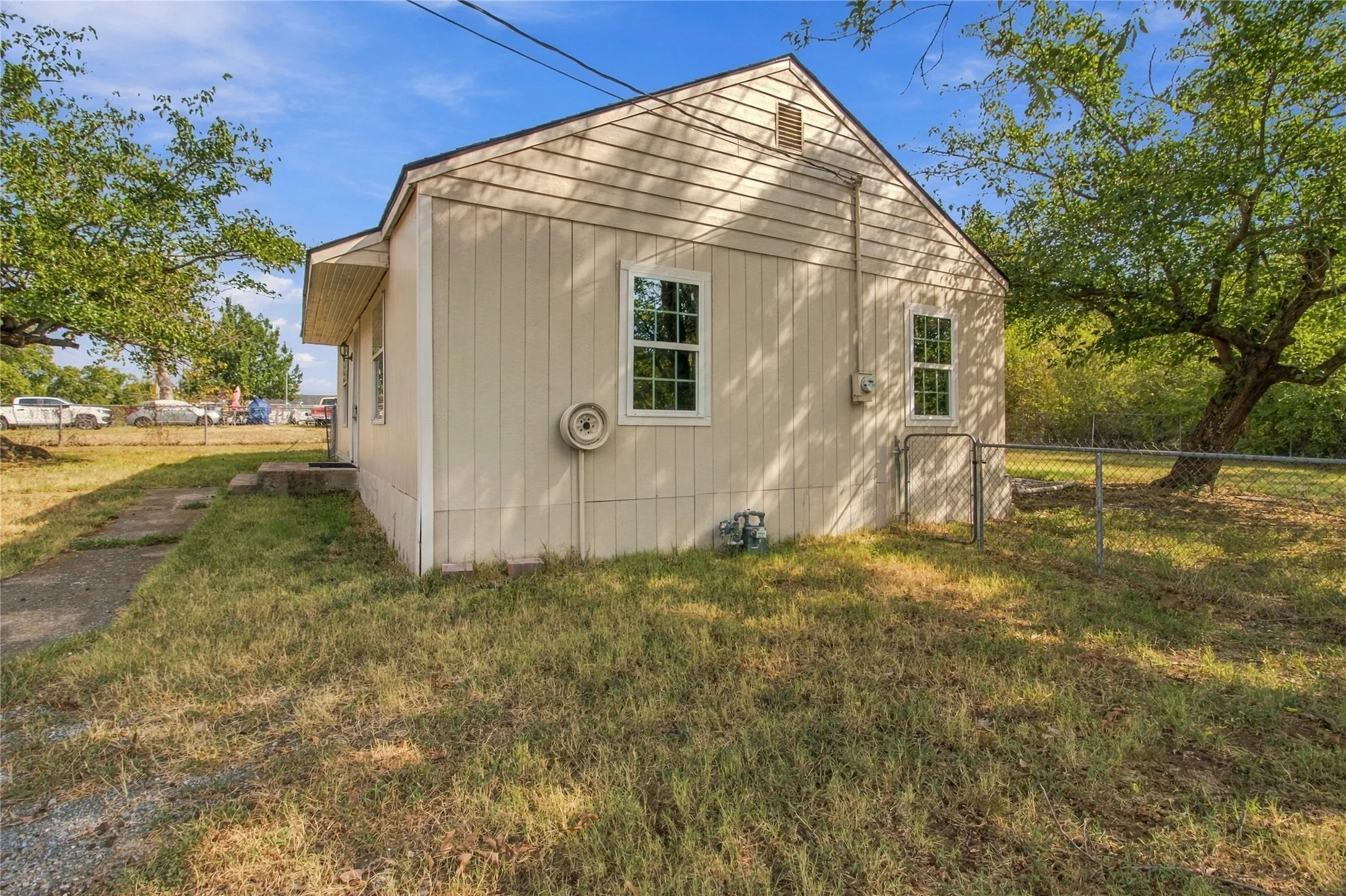 Exterior featuring neutral-toned siding, white-framed windows, and a chain-link fence