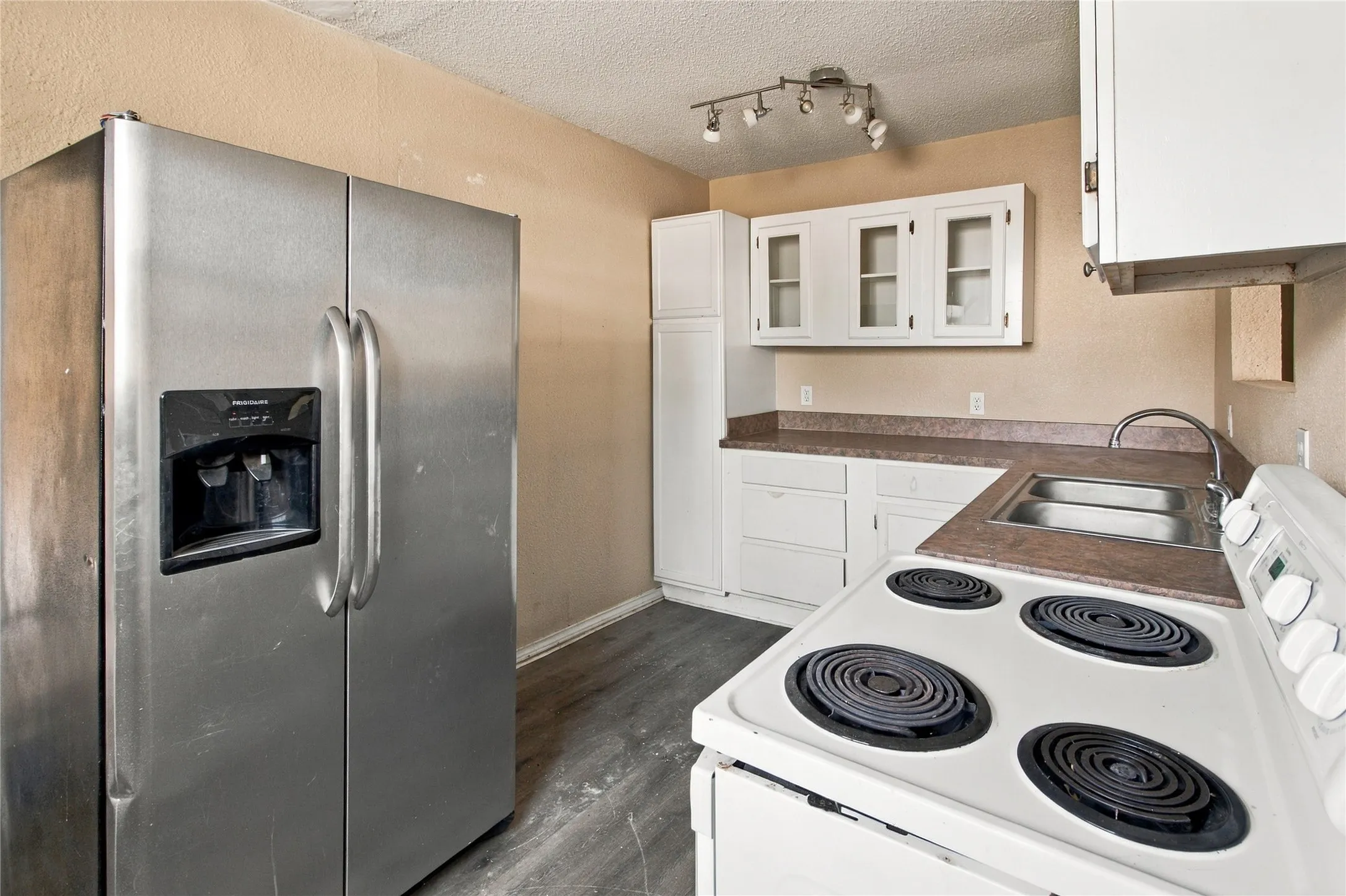 Kitchen featuring a stainless steel side-by-side refrigerator, white cabinetry, laminate countertops, and a double basin stainless steel sink