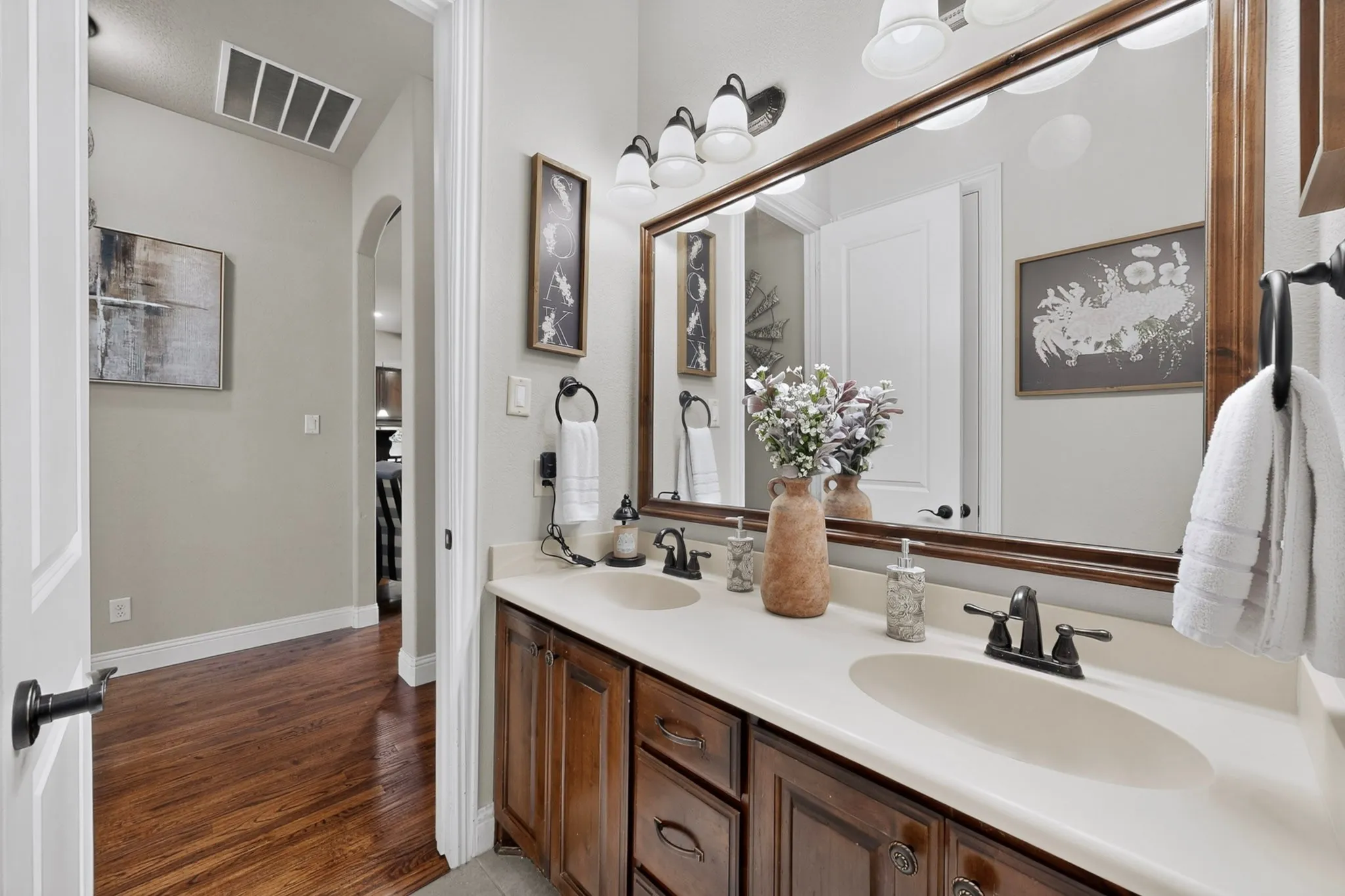 Double vanity with integrated sinks, dark wood-finish cabinetry, and a large framed mirror with overhead lighting