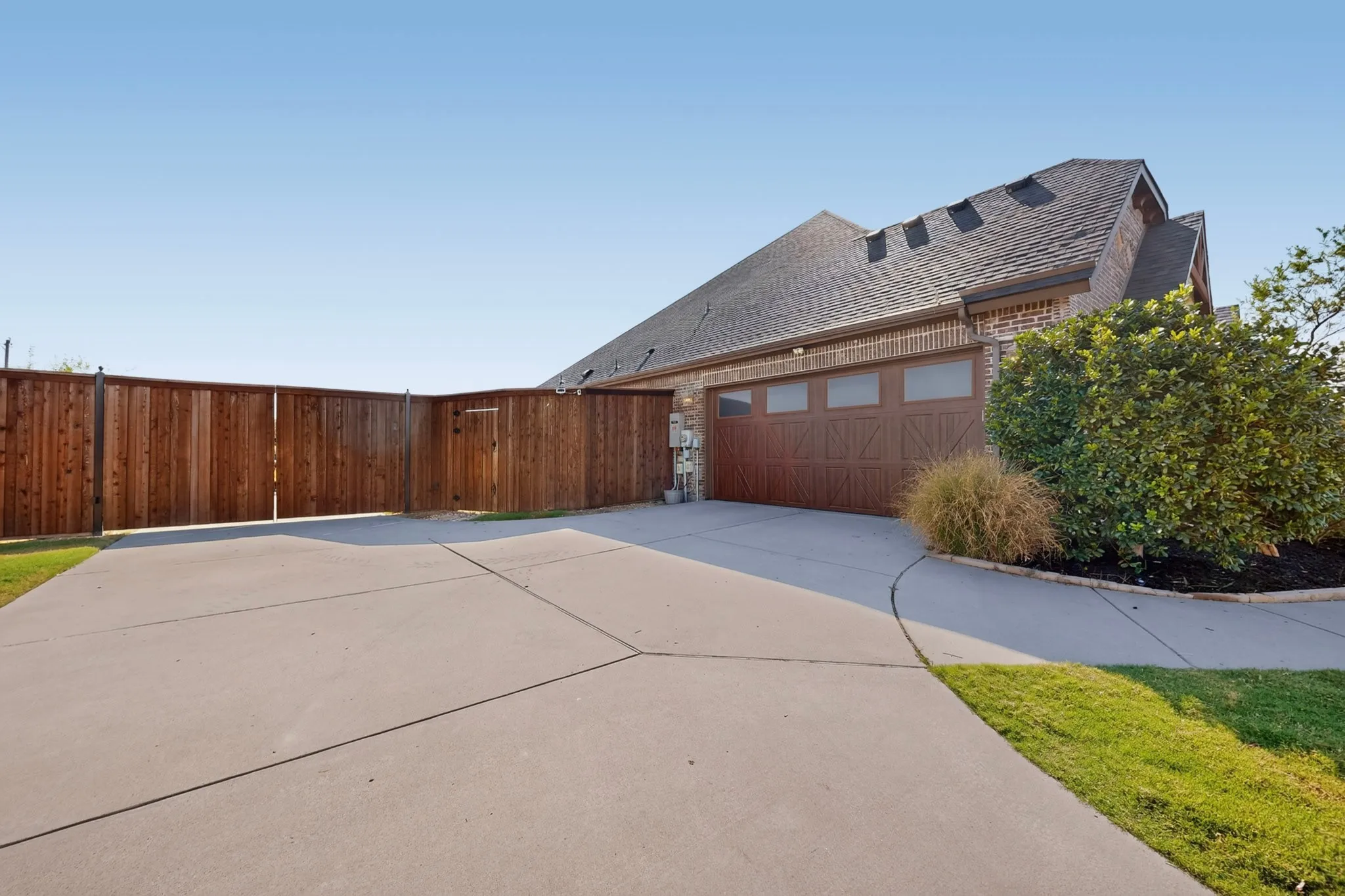 Concrete driveway with an integrated walkway, leading to a multi-car garage with a wood-finish door and frosted windows