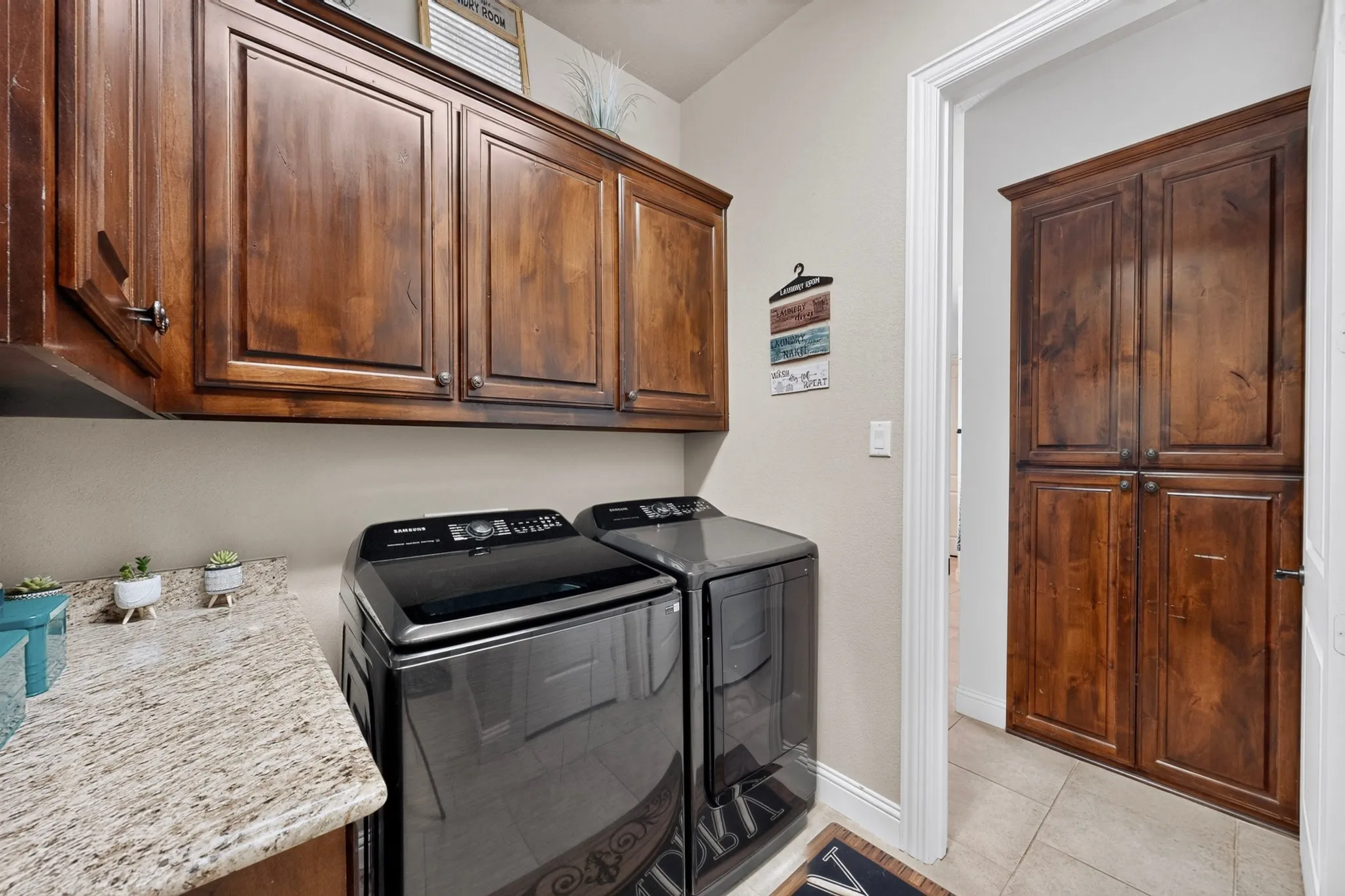 Built-in cabinetry, granite-style countertop, and tiled flooring