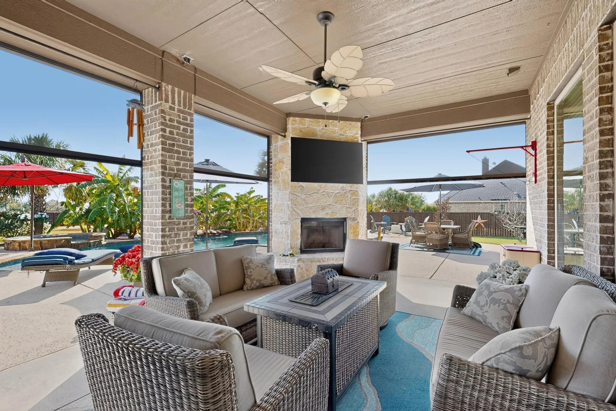 Covered patio with brick and stone accents, a built-in fireplace, and a ceiling fan