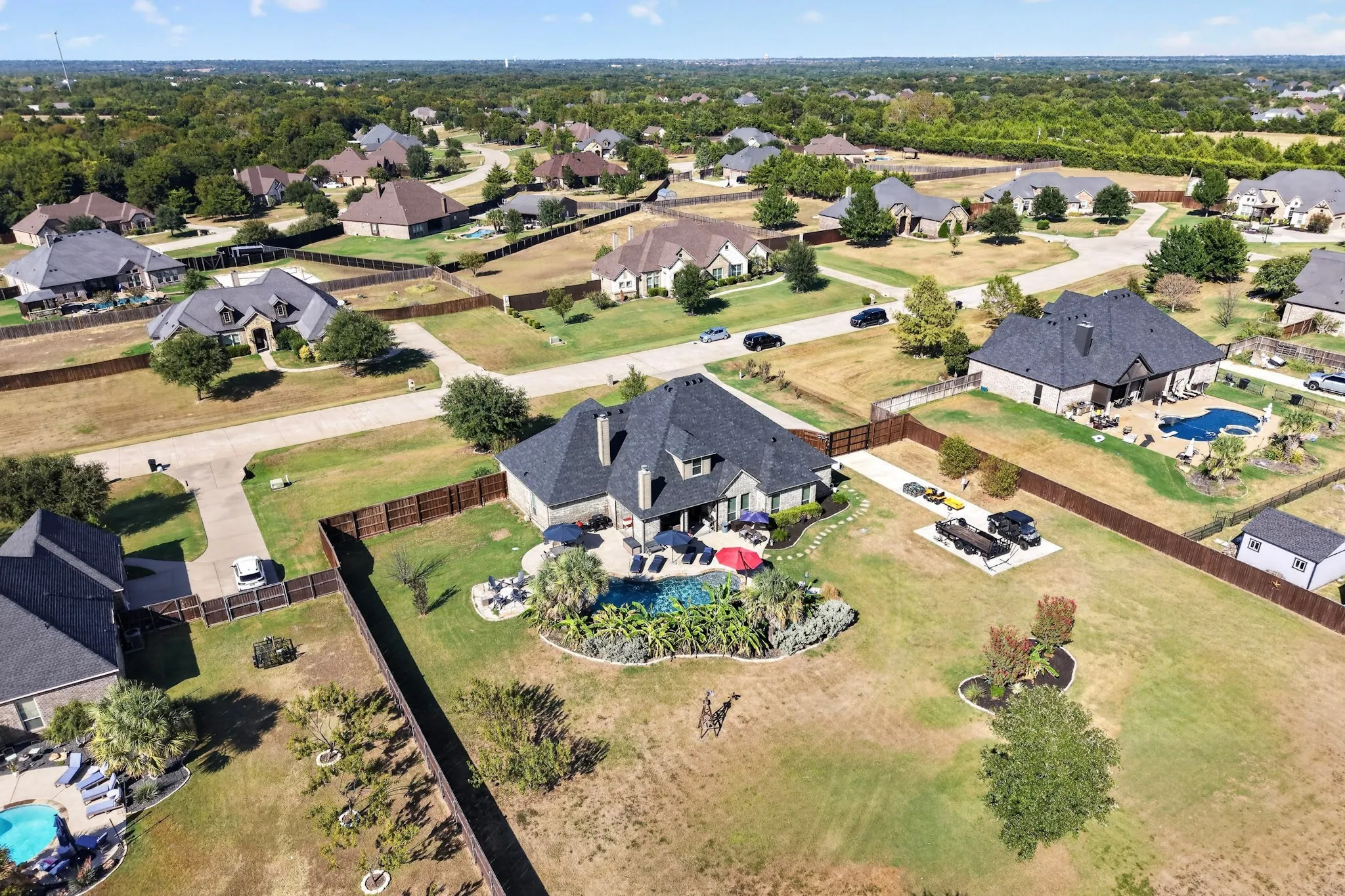 Expansive residential property with an in-ground swimming pool, a dedicated pool deck, and mature landscaping