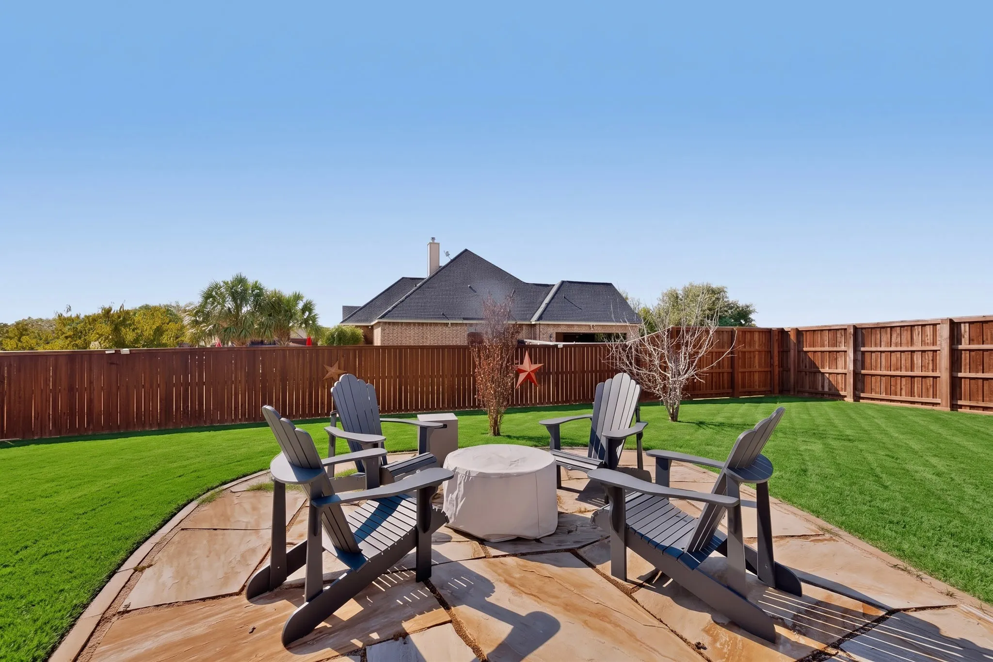 Expansive backyard featuring a stone patio, manicured lawn, and privacy fencing