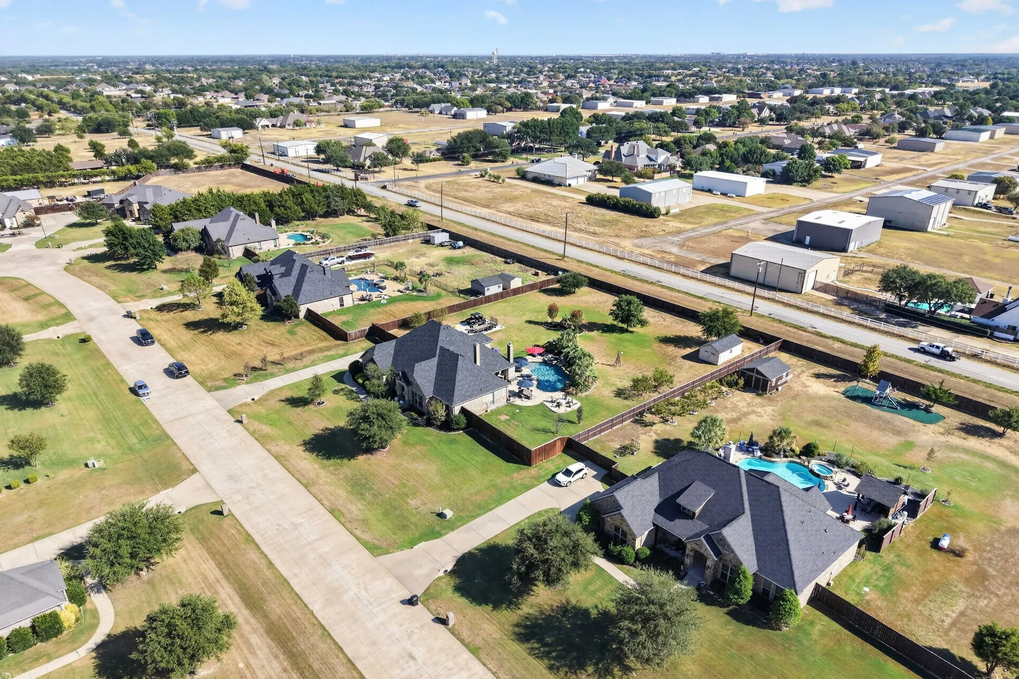 Aerial view showcasing two contemporary residences with dark architectural roofing, manicured lawns, and mature landscaping