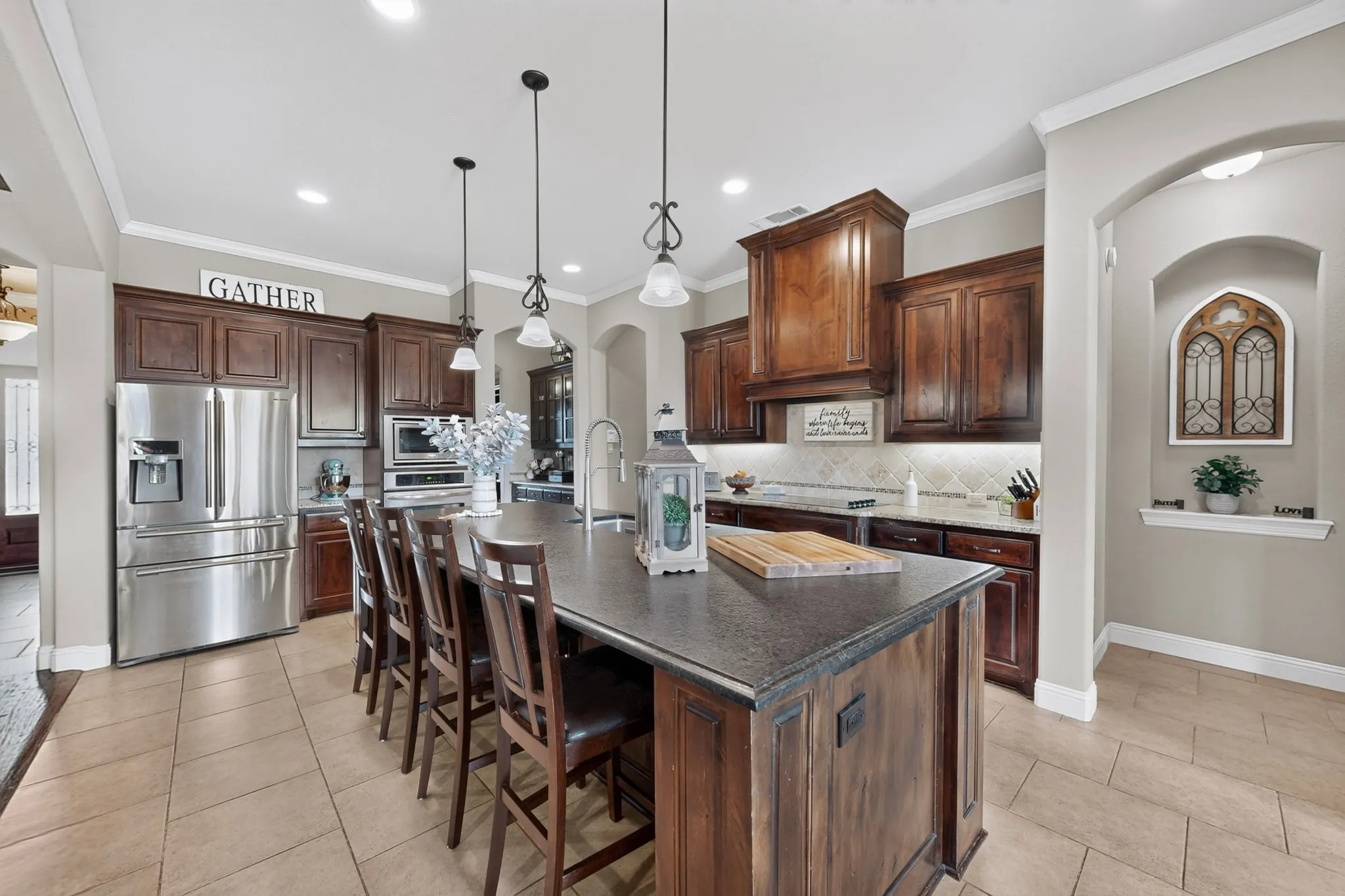 Spacious kitchen with a large island, wood-finish cabinetry, stainless steel appliances, and tiled flooring