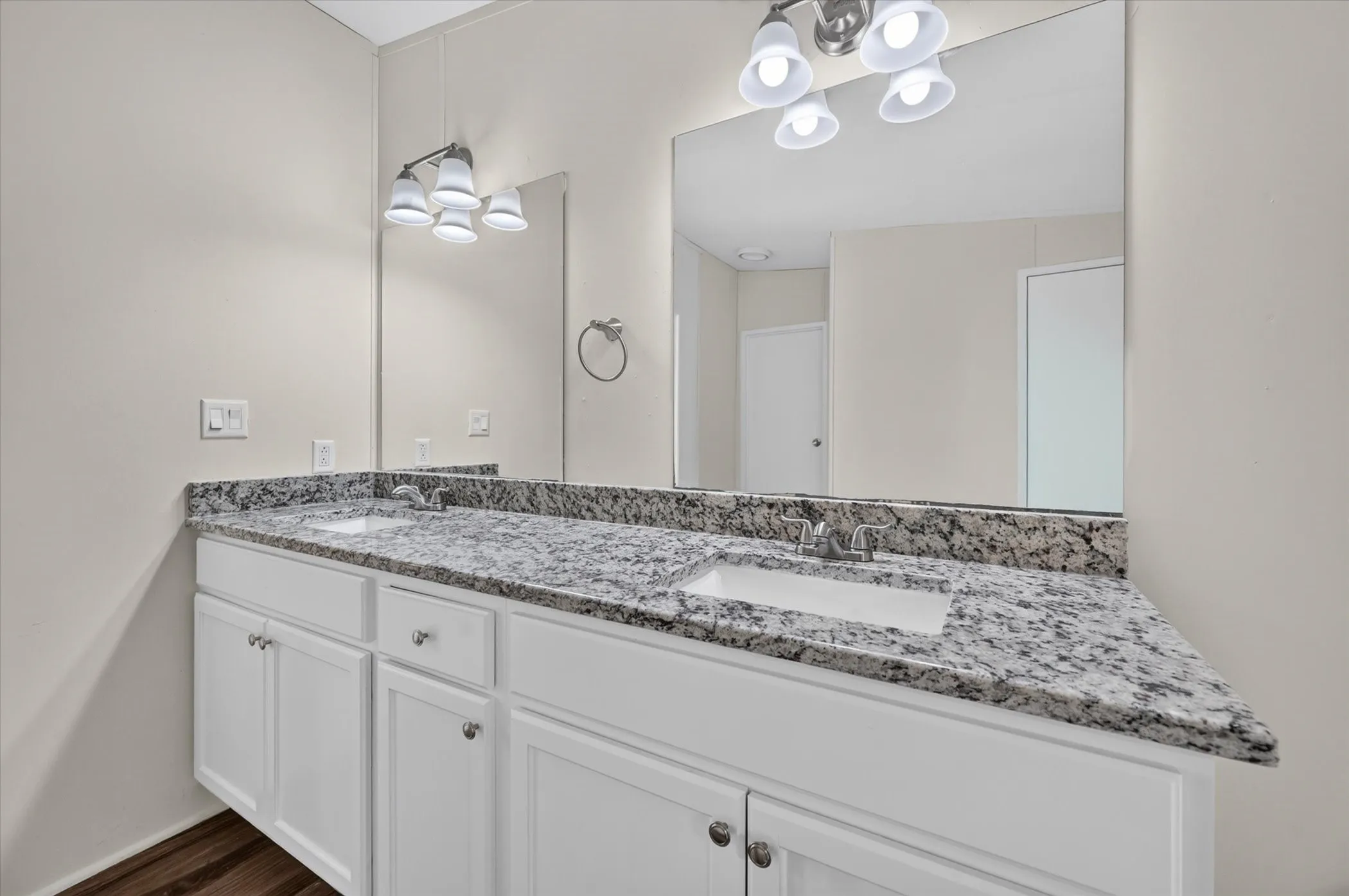 Dual vanity with white cabinetry, granite-finish countertop, and undermount sinks