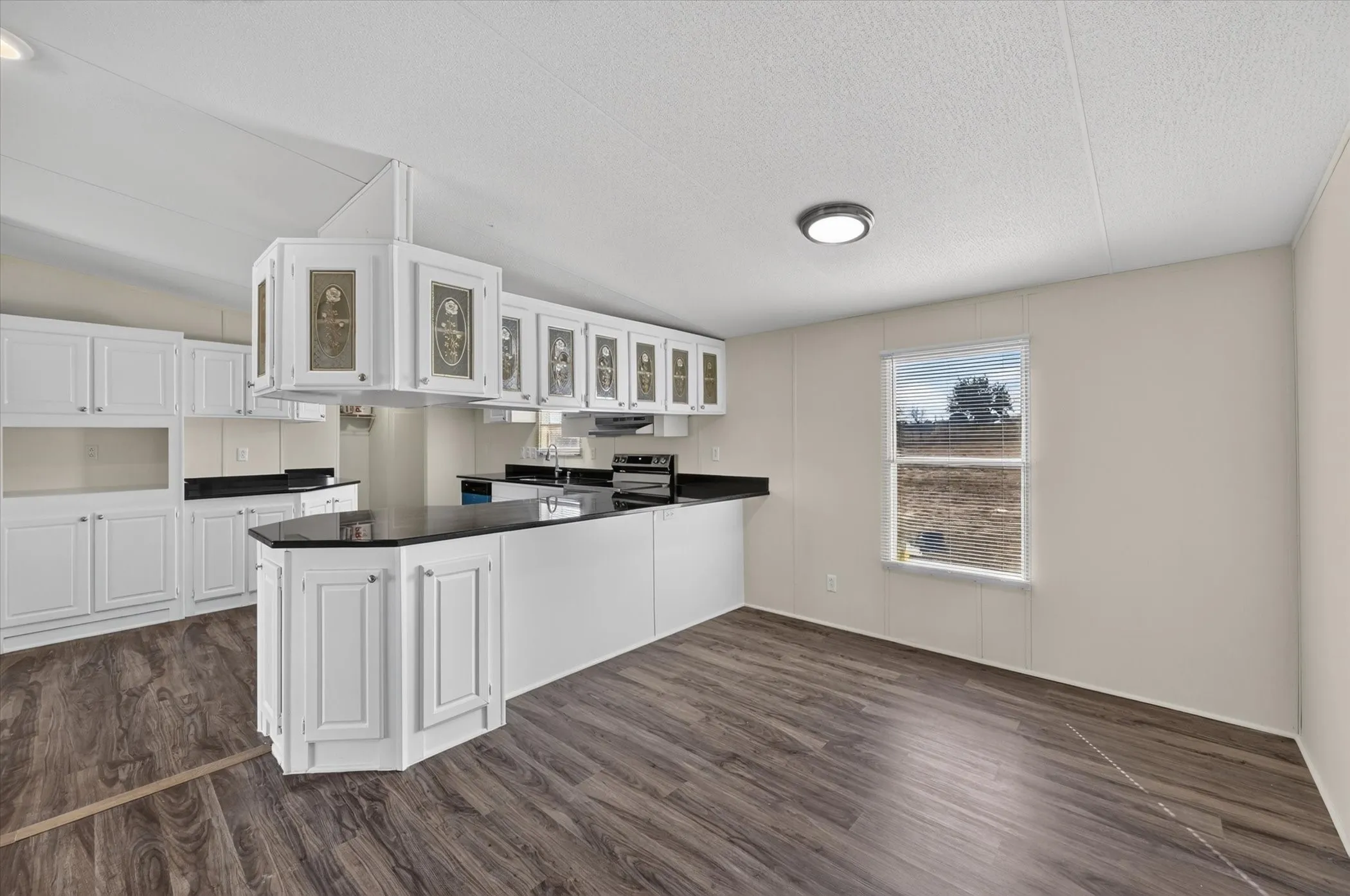 Open-concept kitchen with white cabinetry and dark countertops