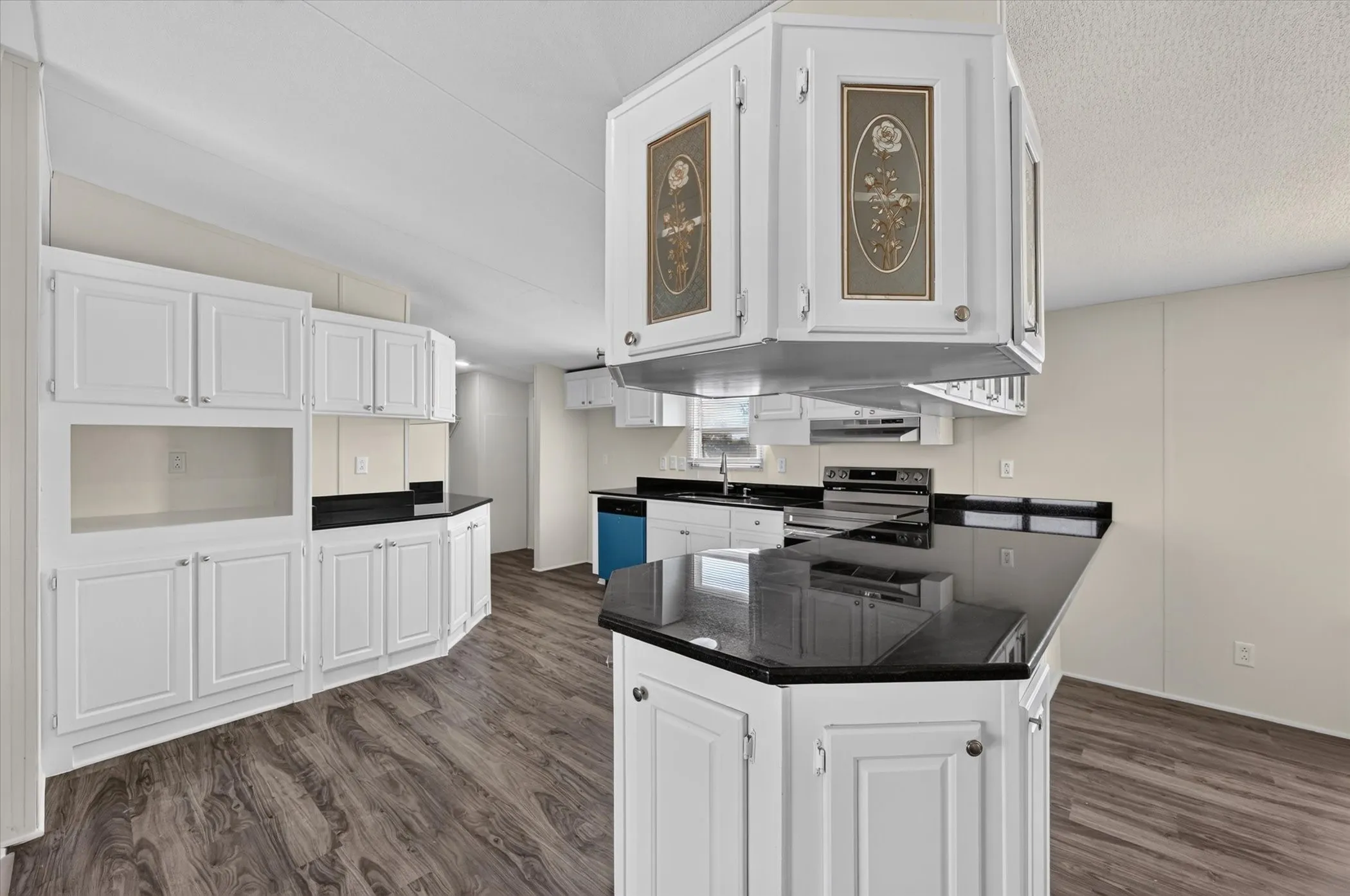 Kitchen featuring white cabinetry, dark countertops, wood-finish flooring, a stainless steel range, and a built-in dishwasher