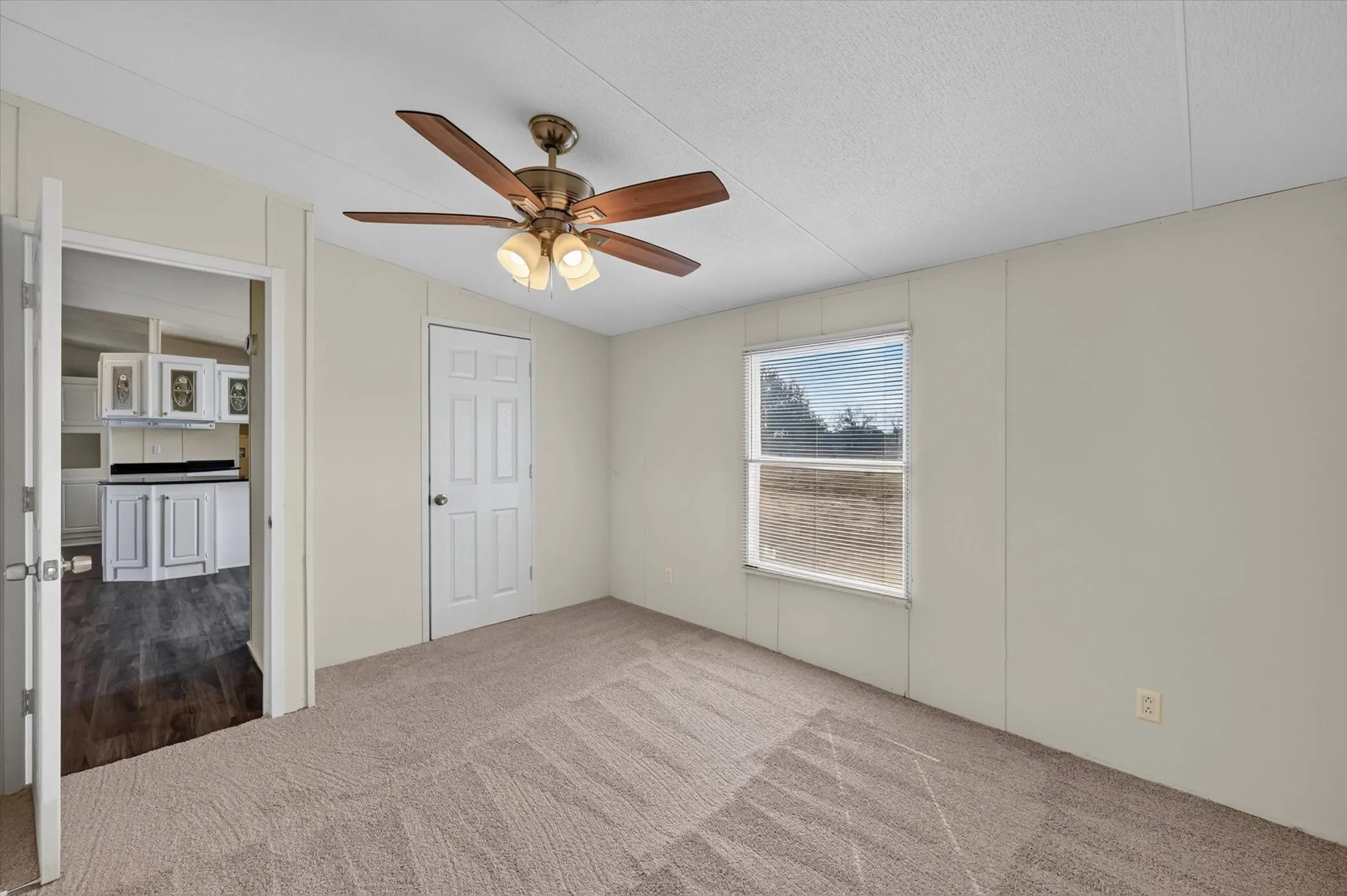 Carpeted flooring, ceiling fan with integrated lighting, white paneled door, and a single window with blinds