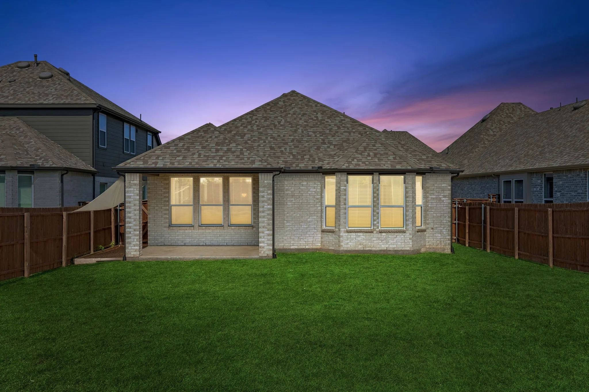 Light-colored brick exterior with dark trim accents, arched entry, dormer window, and an attached garage