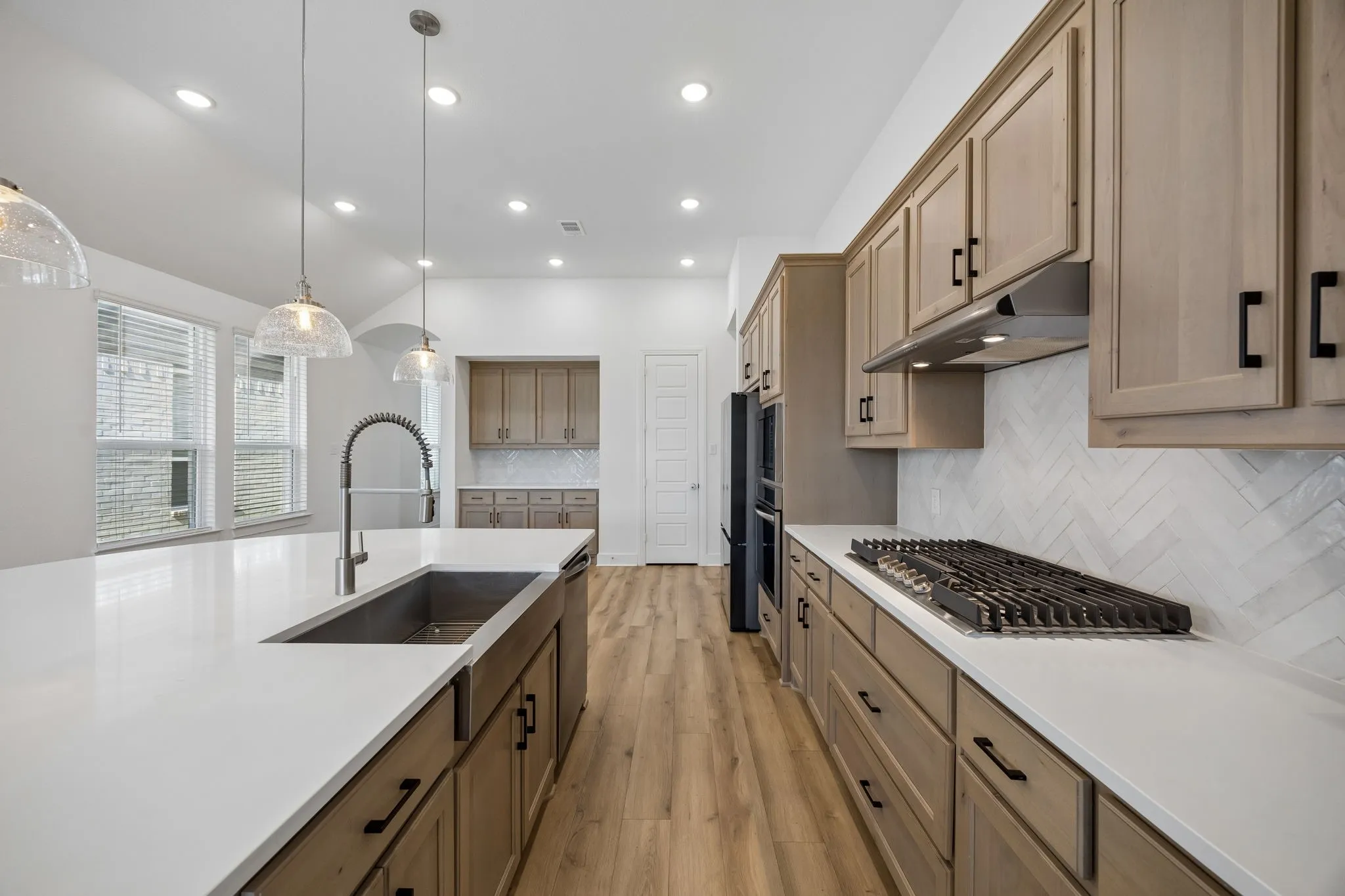 Vaulted ceiling with a ceiling fan, wood-finish flooring, three large windows with blinds, and a built-in media niche