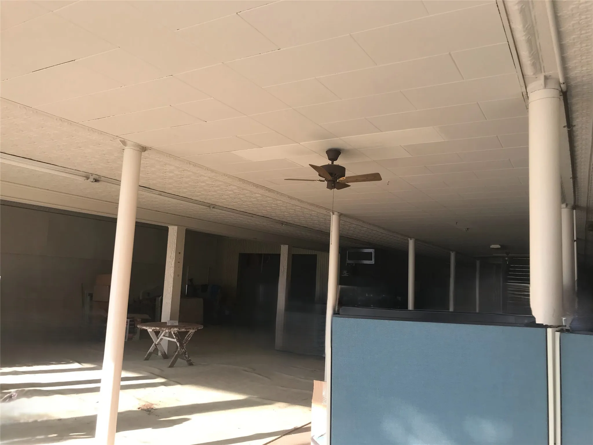 Recessed grid ceiling panels, wood-finish ceiling fan, and structural columns