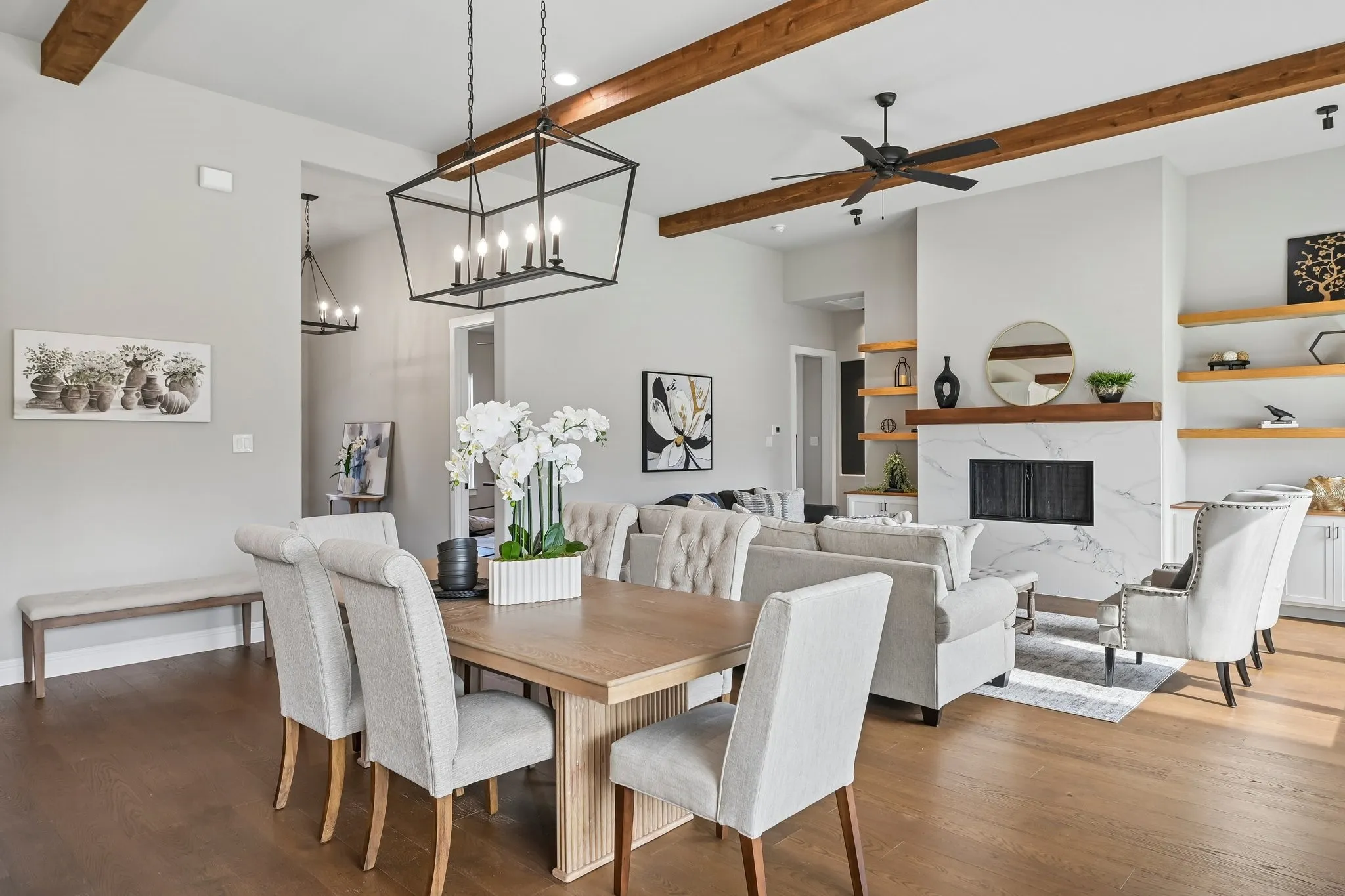 Vaulted ceiling with exposed wood beams, wood-finish flooring, recessed lighting, and a fireplace with a white stone surround and wood mantel