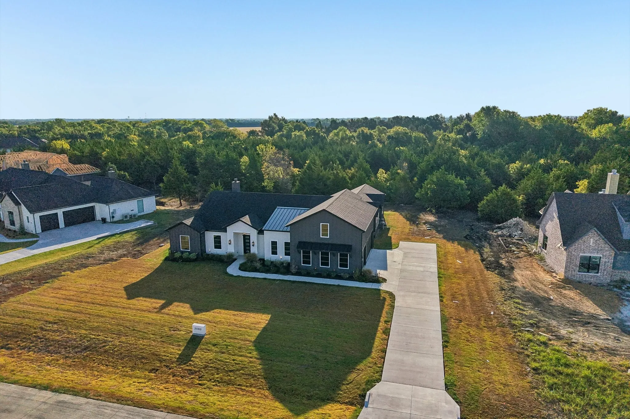 Newly constructed home featuring a modern farmhouse aesthetic with dark exterior siding, white trim accents, and a metal roof