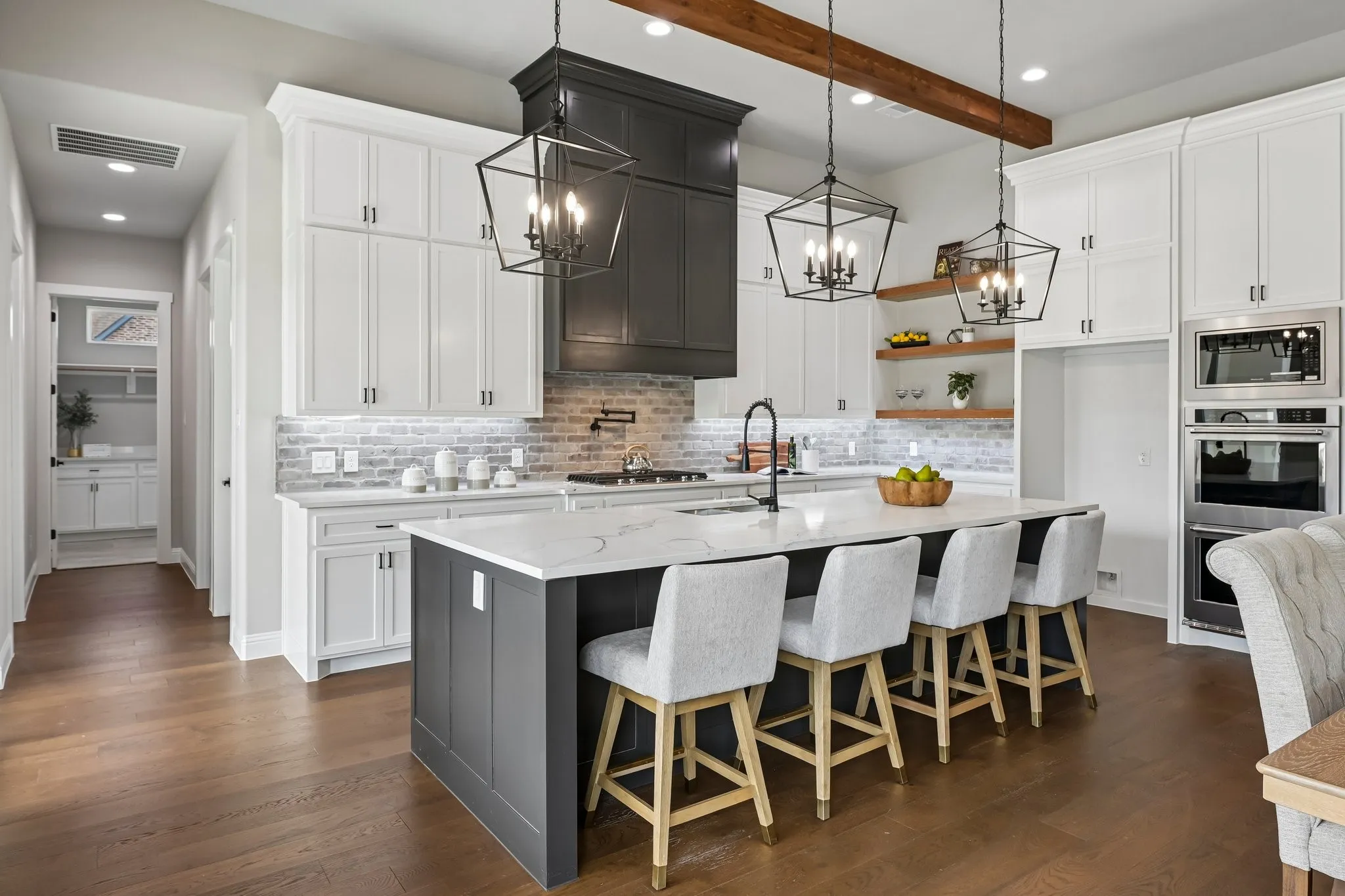 Gourmet kitchen with wood-finish flooring, white cabinetry, a large kitchen island with counter seating, stainless steel double ovens, and a built-in microwave