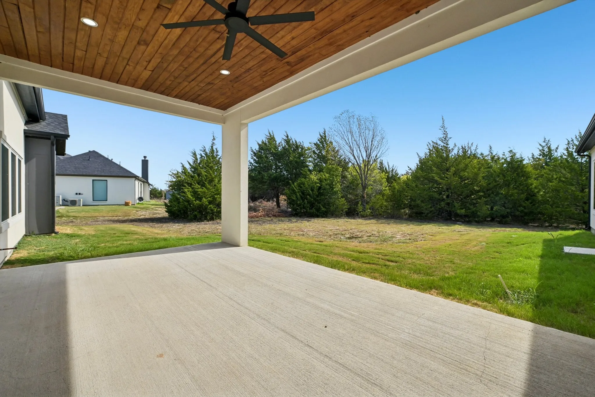 Covered concrete patio with a wood-plank ceiling, recessed lighting, and a ceiling fan