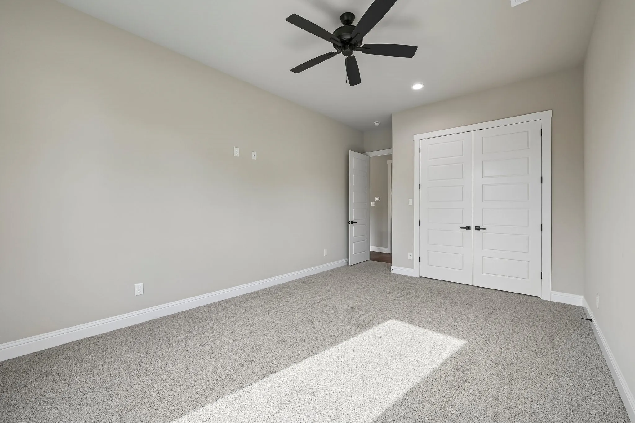 Recessed lighting, ceiling fan with matte black finish, light gray carpet, and white paneled doors with matte black hardware