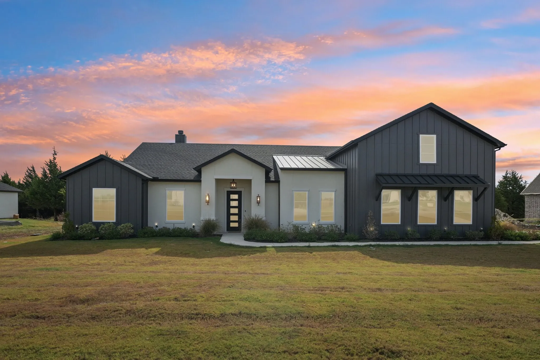 Modern farmhouse-inspired exterior with dark vertical siding, light-toned stucco, and a dark shingle roof