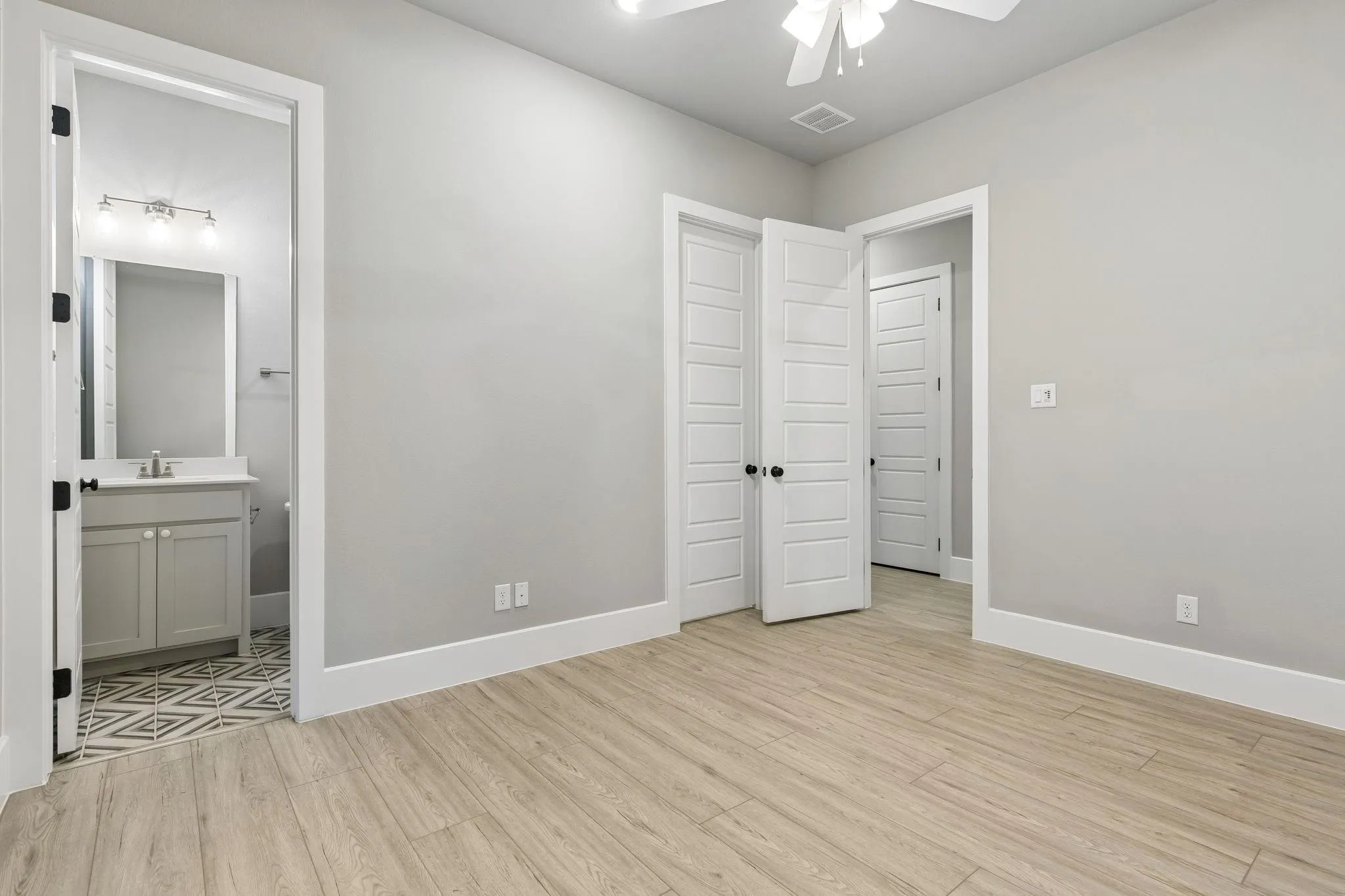 Light wood-finish flooring, white paneled doors, neutral wall paint, ceiling fan, and recessed lighting