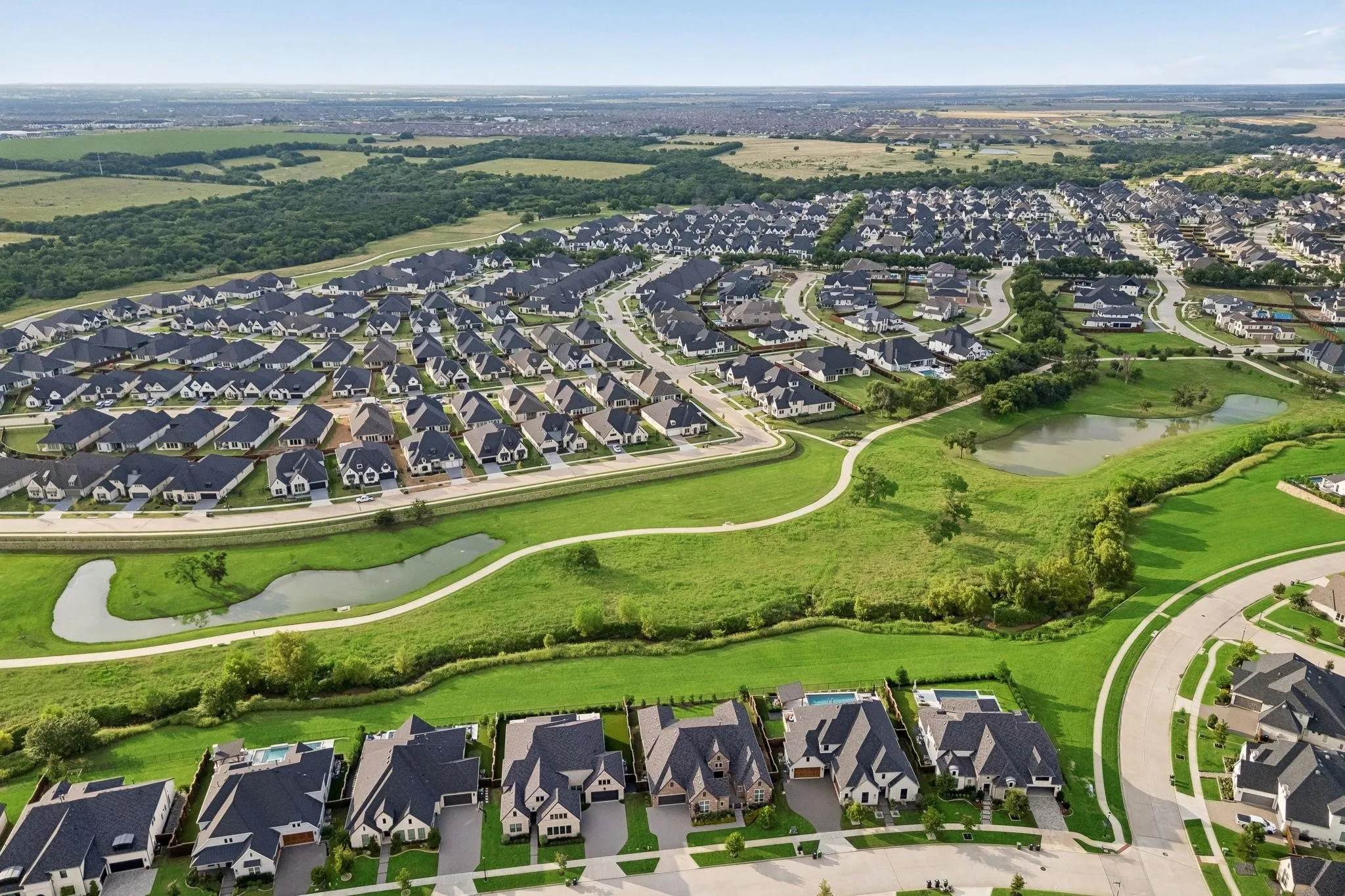 Expansive community featuring residential properties, curved roadways, and green spaces