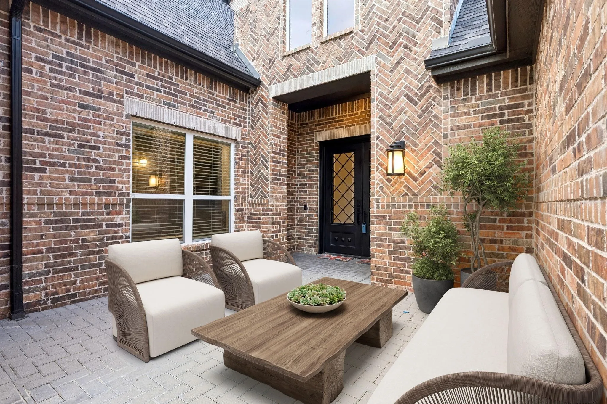 Brick exterior with varied patterns, paver patio, prominent entry door with decorative glass, and exterior wall sconce